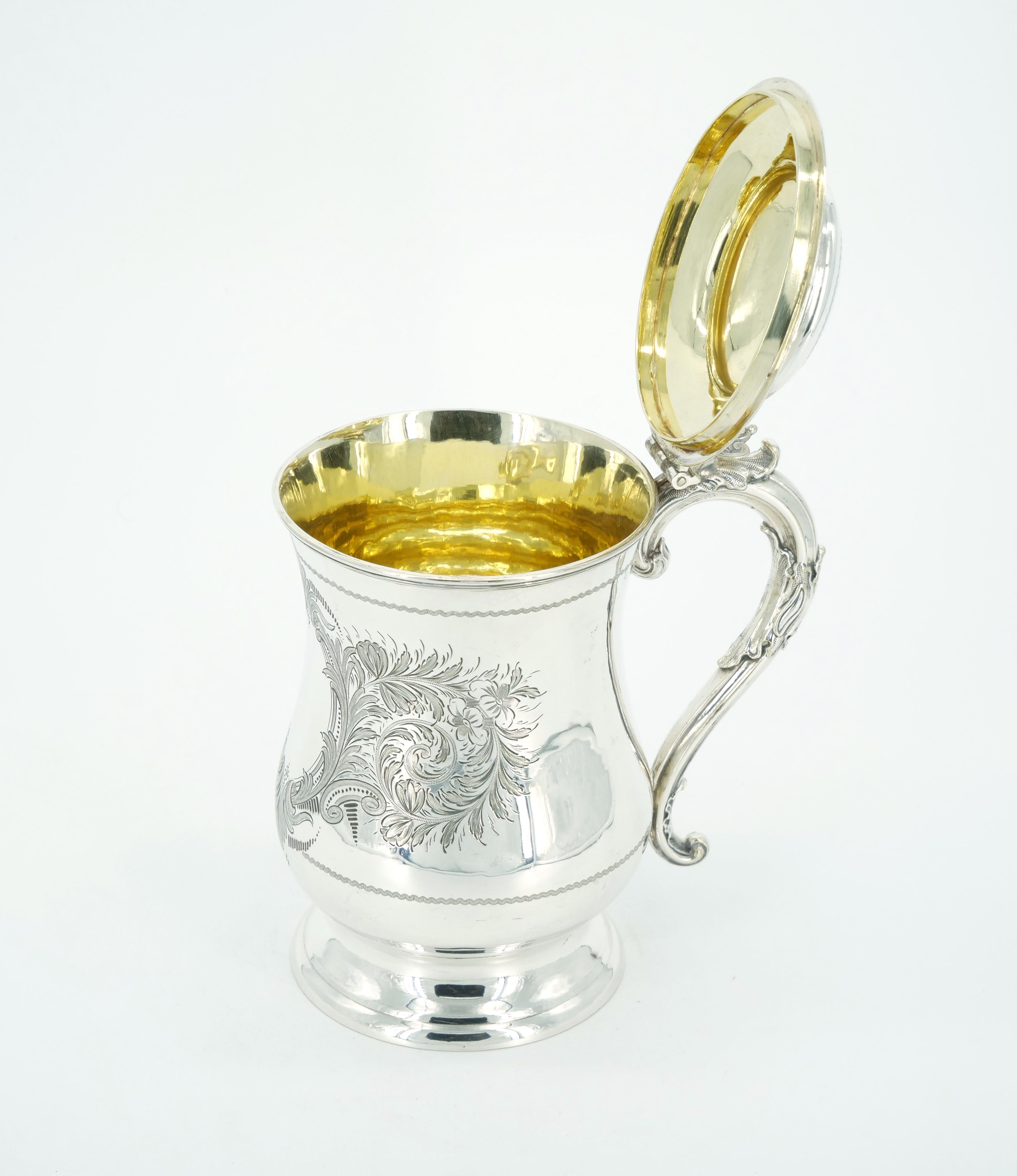 Immerse yourself in the timeless allure of our Old English Silver Plate Queen Anne Tankard, an extraordinary piece featuring a captivating blend of craftsmanship and design elements. The exterior is adorned with intricate engraved foliate decoration