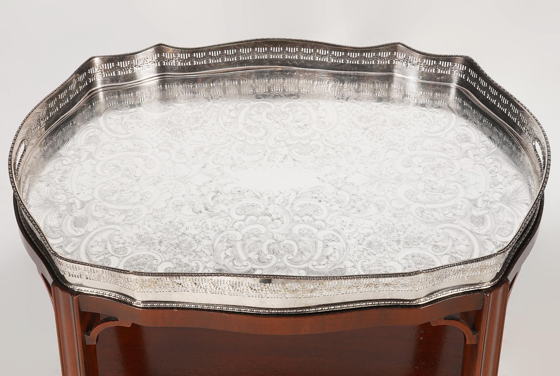 This elaborately chiseled silver plate tray with reticulated gallery rests on a custom made Chippendale mahogany stand with slightly splayed legs united by a shaped lower shelf, 20th century. The tray is resting on a velvet lined surface and has a