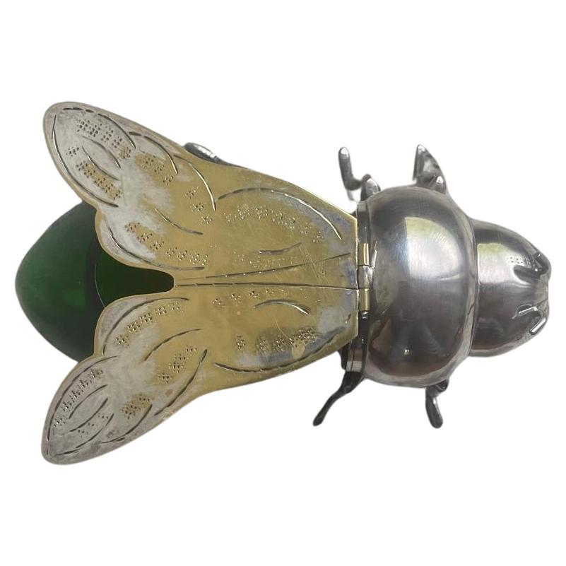 A charming and rare silver-plated figural honey pot, crafted in the shape of a stylized honey bee, England, early 20th century. This whimsical piece is composed of a finely chased silver-plated head and legs, paired with a rich emerald green blown