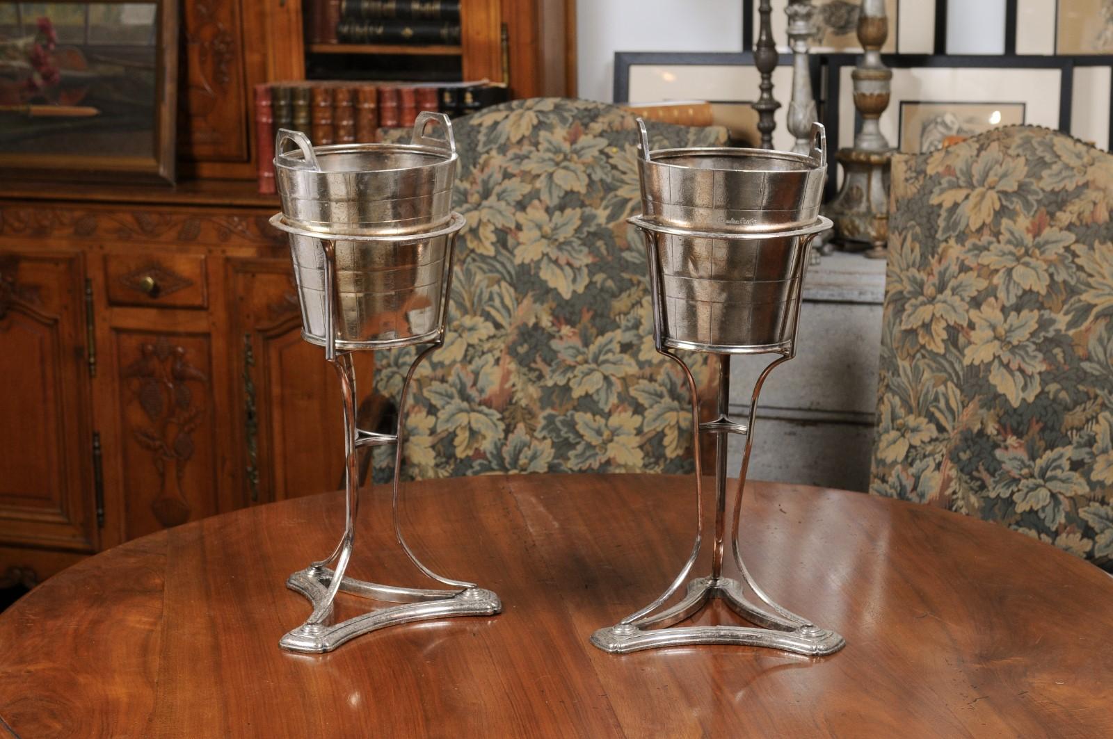 A pair of English vintage silver plated champagne buckets from the 20th century, made for a Canadian Pacific Railway train. Created in England during the 20th century, each of this pair of champagne buckets is mounted on a tripod stand with
