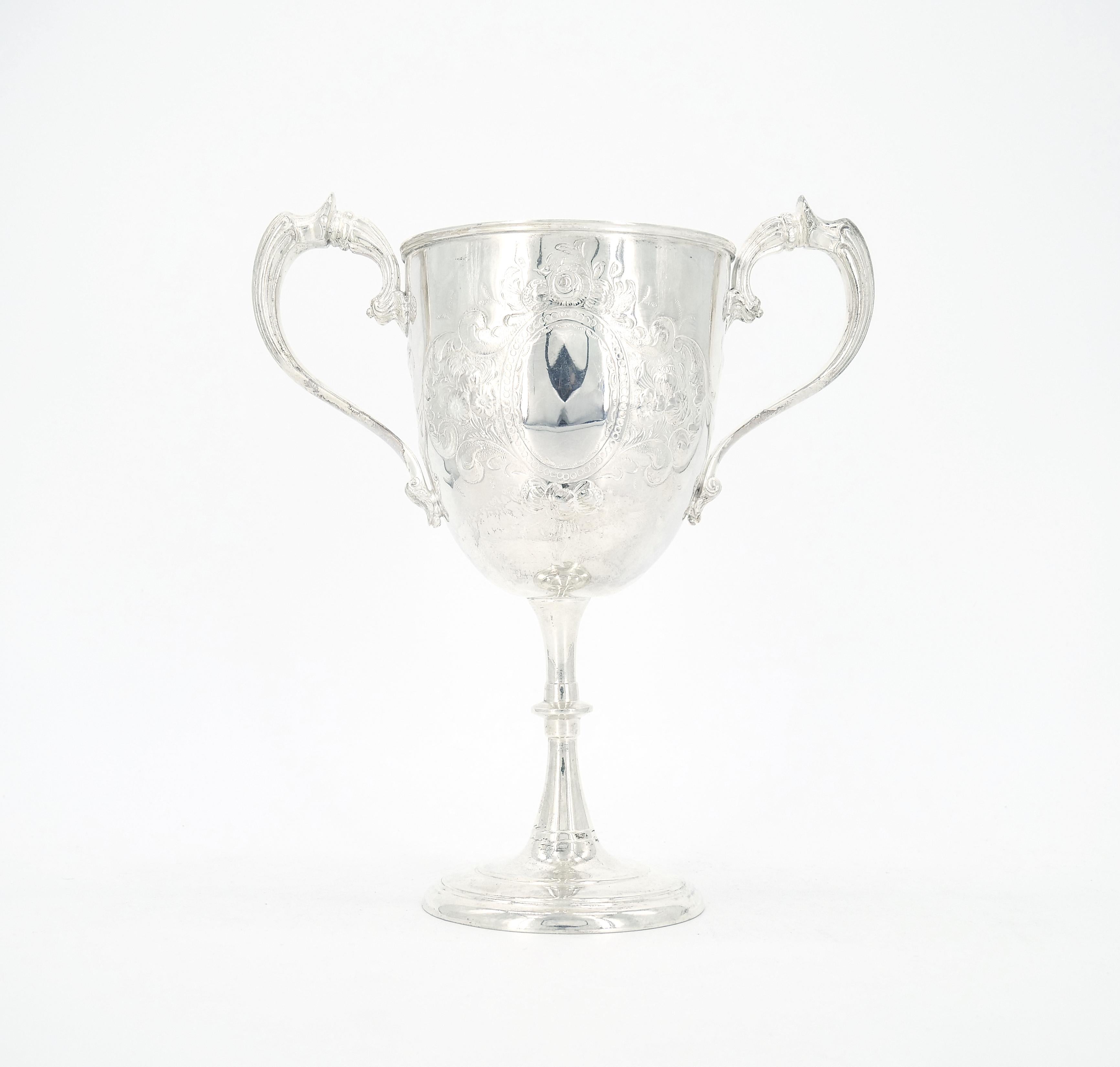 Unveil the epitome of elegance with This English sheffield silver plate two handled trophy cup decorative vase / urn. This remarkable piece, crafted with meticulous attention to detail, doubles as a stunning decorative vase or urn, exuding both