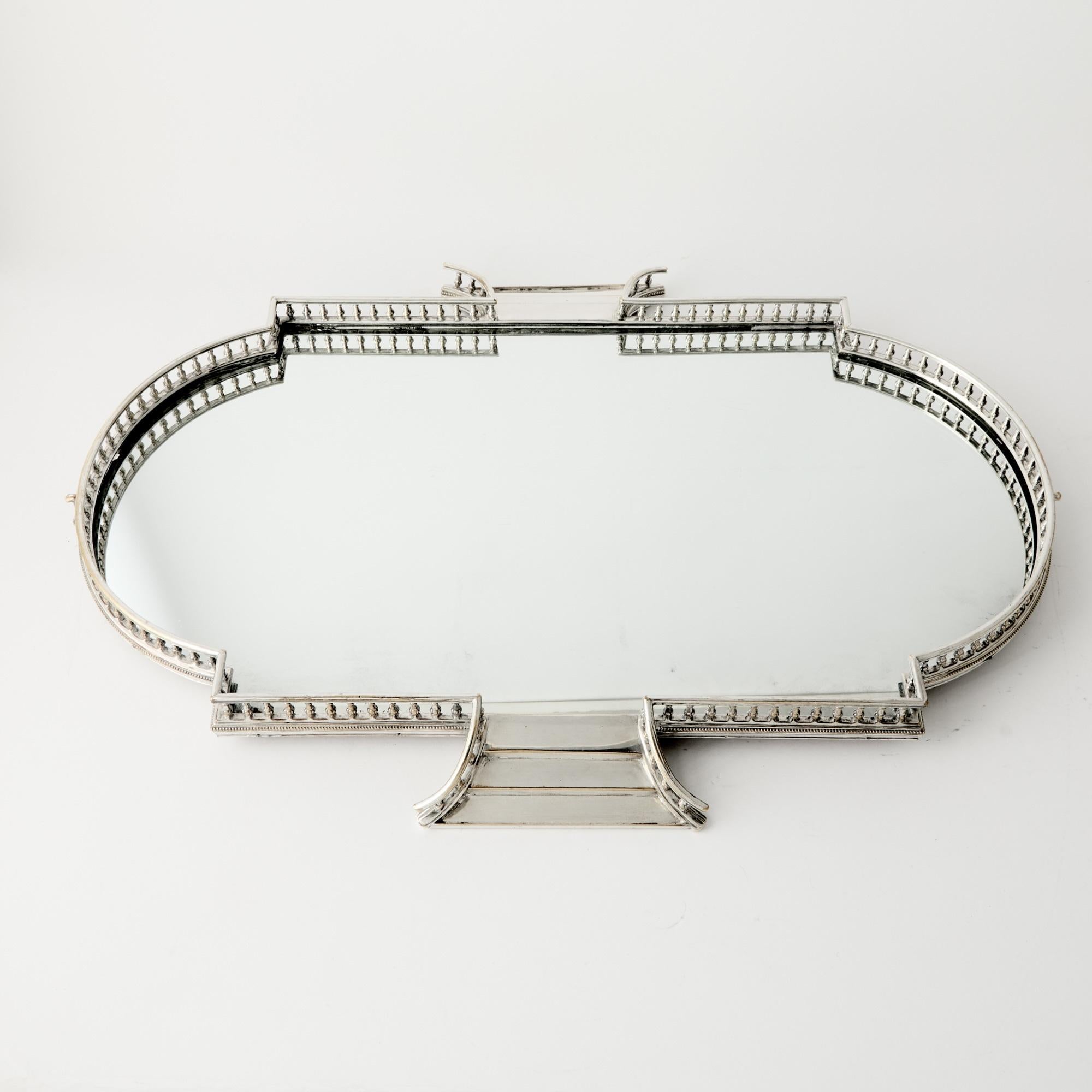 Elegante centro de mesa inglés plateado con espejo de finales del siglo XIX, diseñado en el refinado estilo eduardiano. De forma ovalada, la meseta está enmarcada con lados escalonados y una galería perforada en la parte superior, que descansa