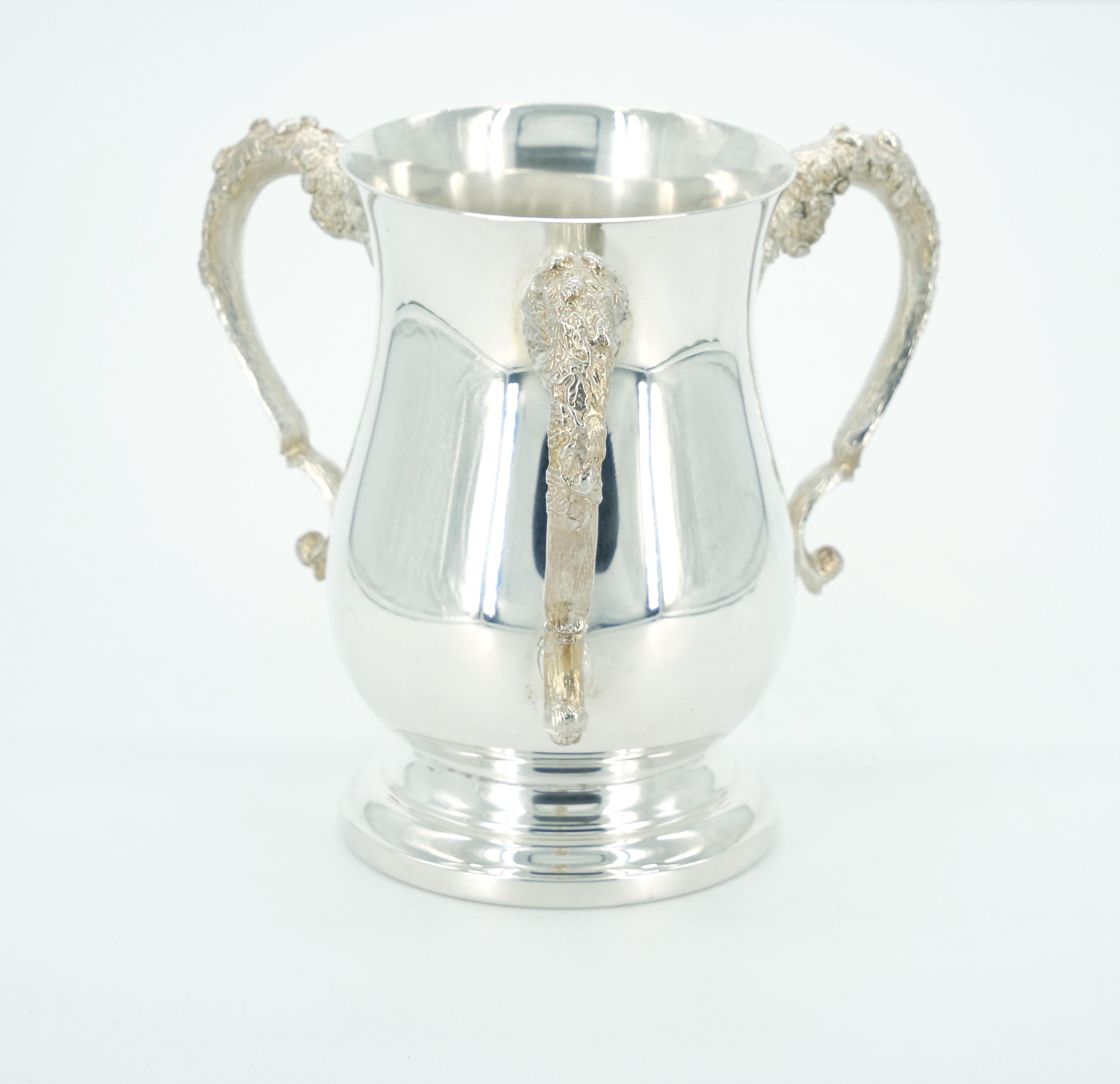 Step into the refined elegance of the 19th century with our English Silver-Plated Three-Handled Cup Vase, perched upon a round footed base. This exquisite piece is a testament to the enduring charm of English craftsmanship, combining intricate