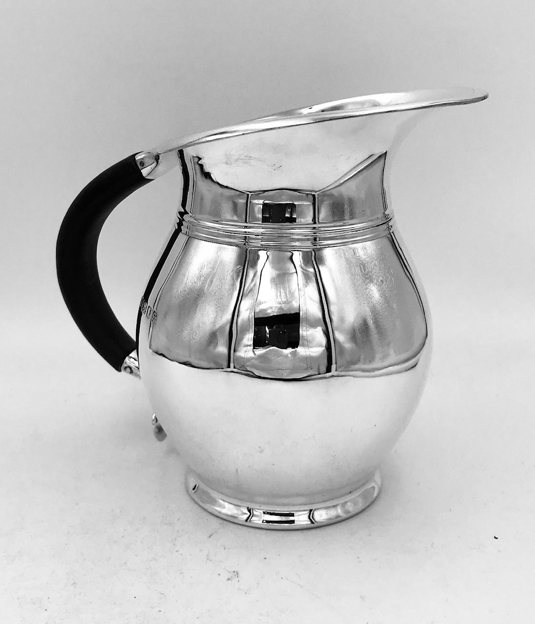 An English sterling silver water jug of unusual design.
This lovely water jug has a wood handle.
Made in London, 1933 by Edward Barnard & Sons.