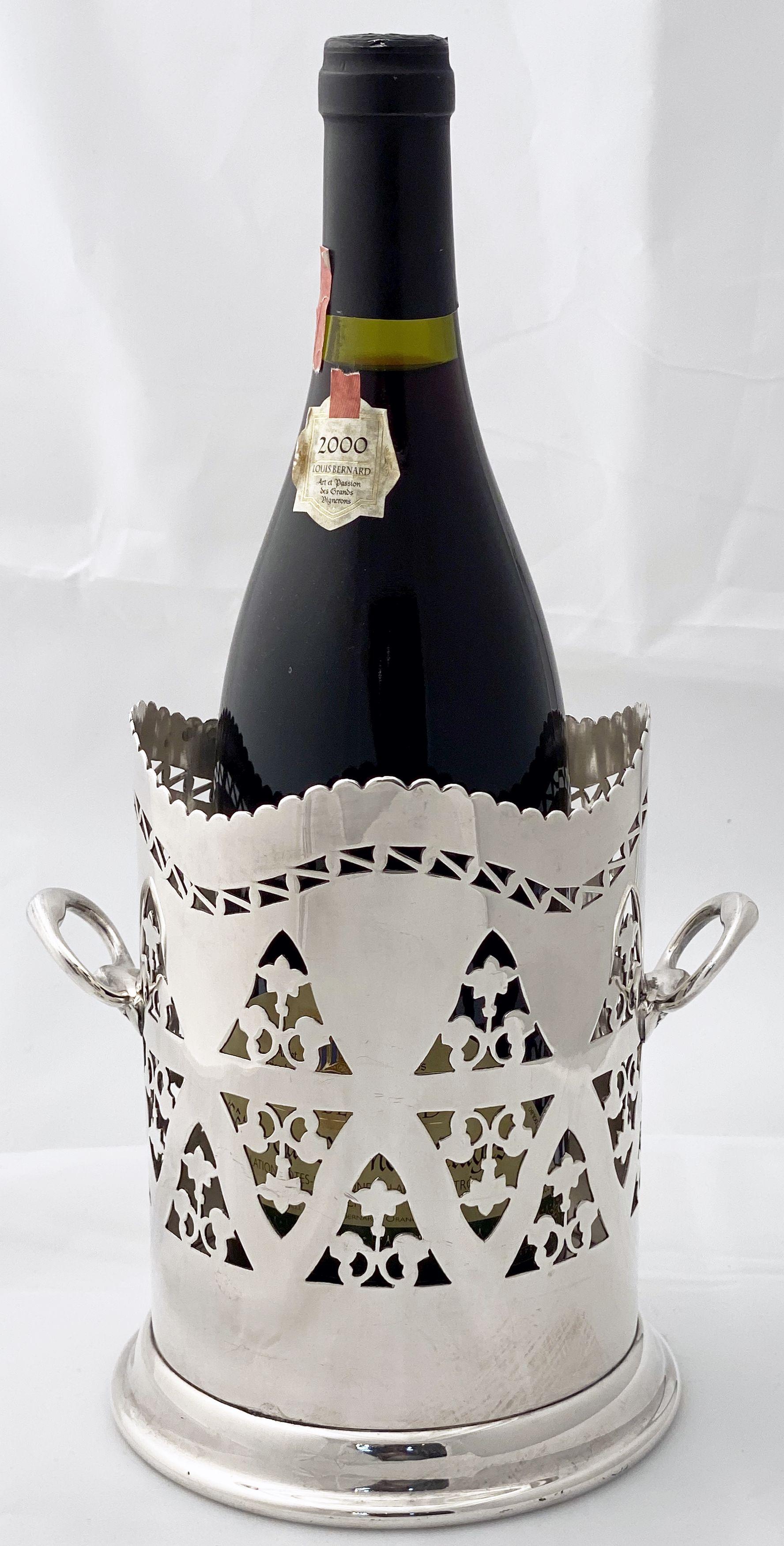 A handsome English wine bottle display holder or coaster of fine plate silver, featuring a serpentine scalloped top edge, pierced design around the circumference, opposing handles, and raised cylindrical base.

Designed to add a fine level of