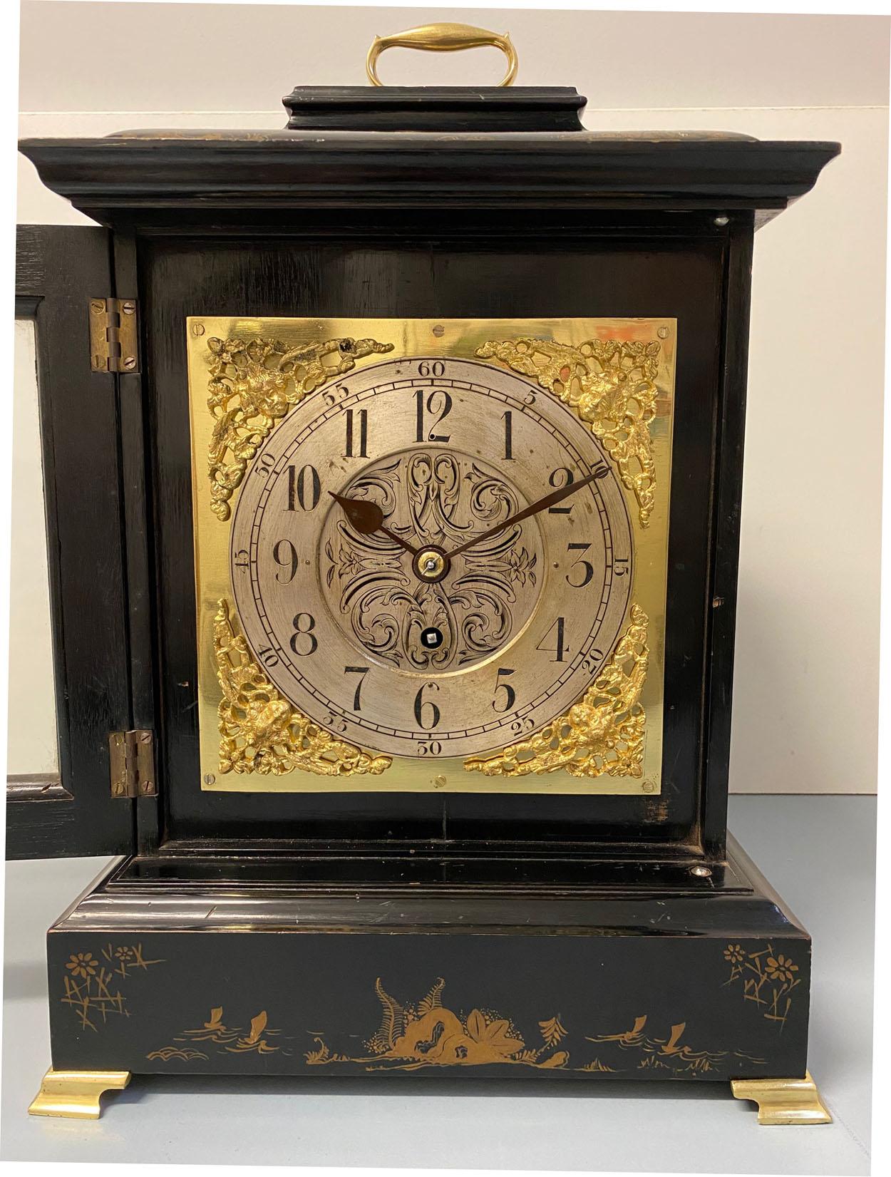 A fine quality English George III style black chinoiserie mantel clock, circa 1880.

The black lacquered wooden case with fine chinoiserie decorations including scenes of trees, ocean, islands, boats, birds and flowers, with brass loop handle, on