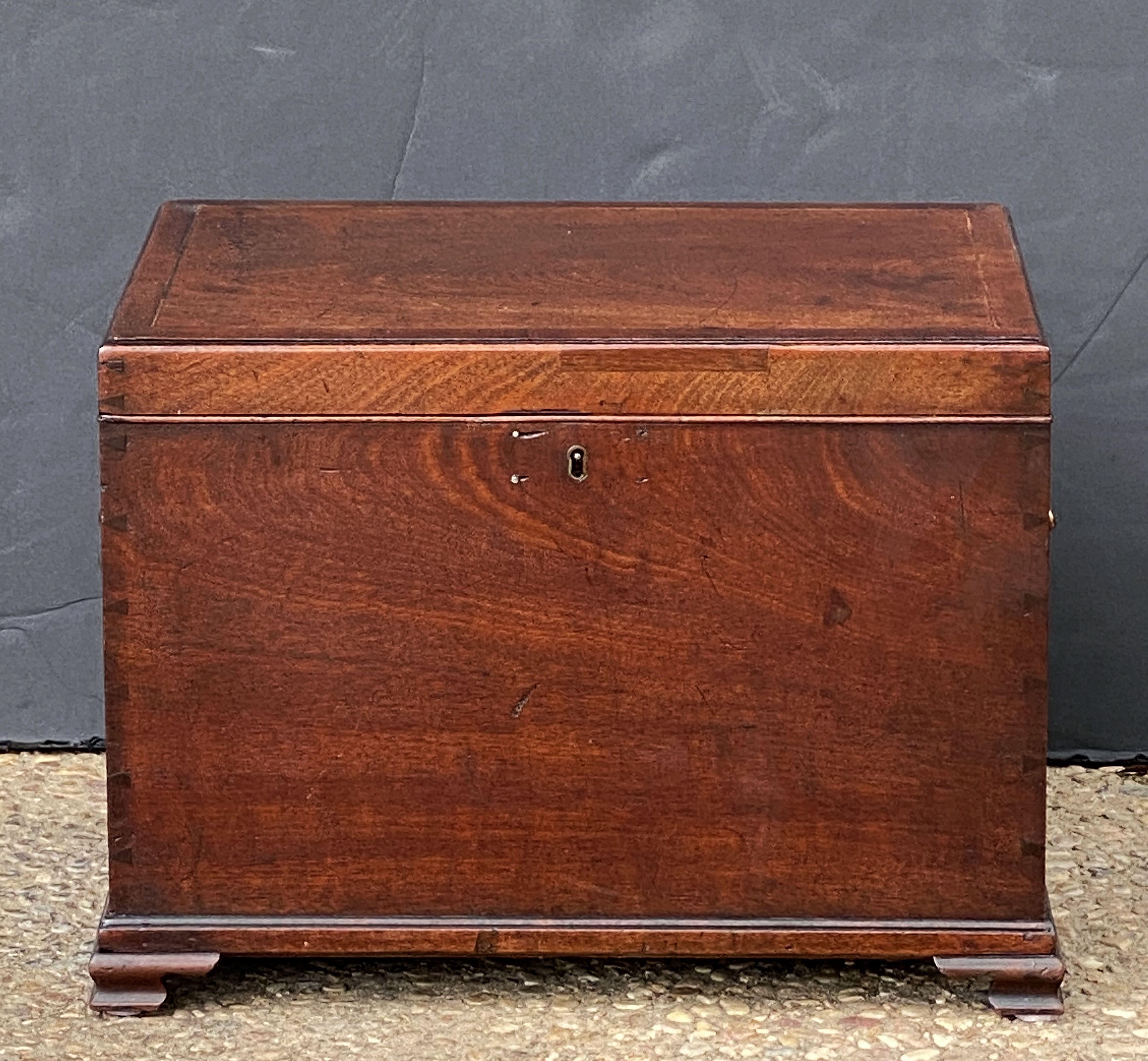A fine period English small chest or box of mahogany from the George III era, featuring a moulded hinge top with inlaid stringing around the circumference, over a rectangular base with swan handles and escutcheon of brass, resting on bracket feet.