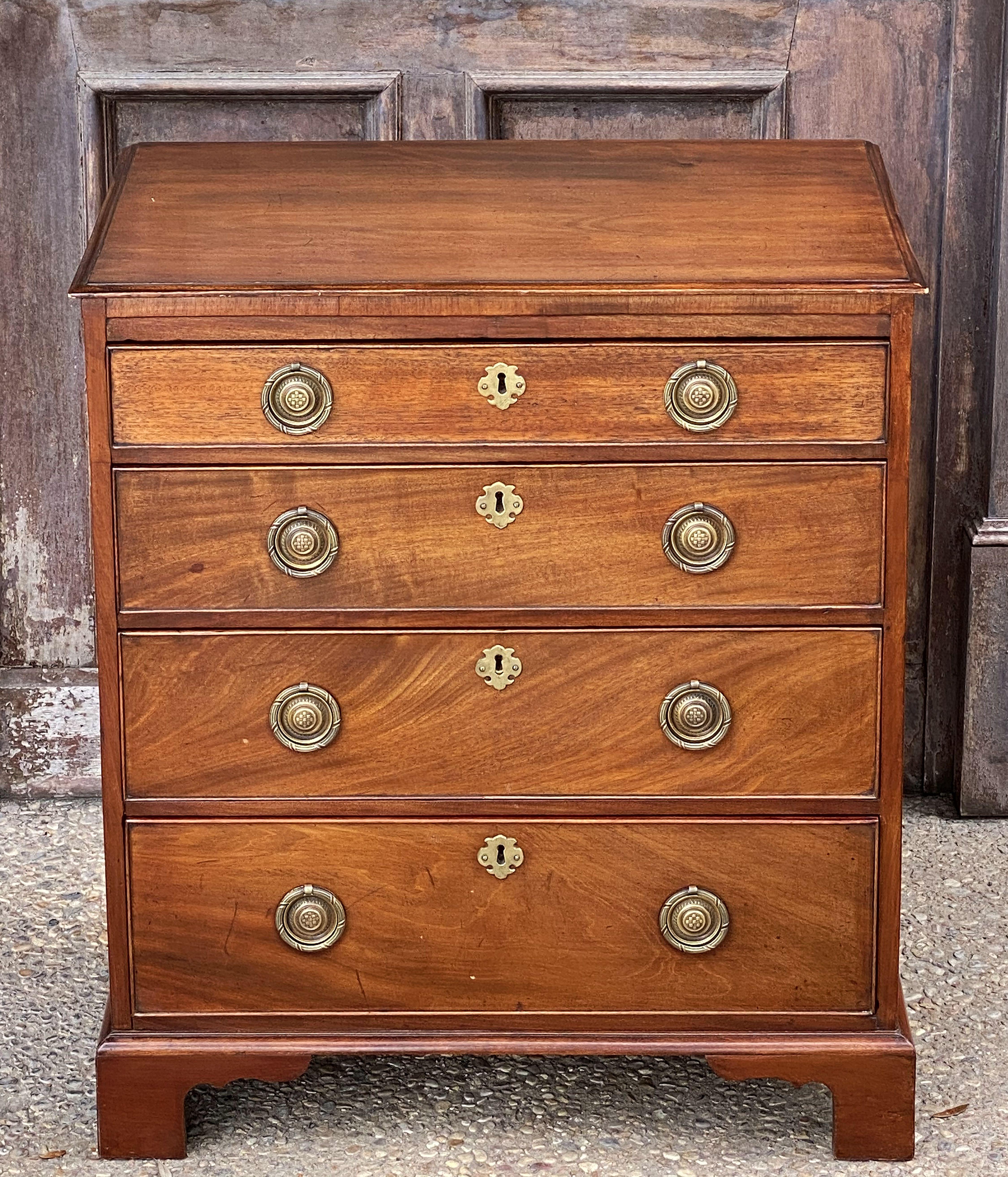 A fine English small chest of mahogany, featuring a moulded top over a frieze of four beaded drawers in ascending size, each drawer with brass ring pulls and brass escutcheon, set upon bracket feet.