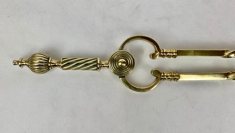 Pair of handsome English Victorian solid brass fireplace tongs. The finial has a melon style motif while the rest of this fire tool has a spiral motif. The pincers at the end are brass rather than the typical iron. This pair of tongs has a nice heft