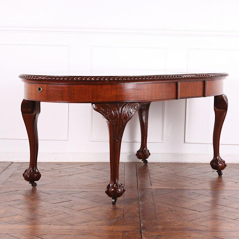 An English Edwardian solid mahogany oval dining table with carved Chippendale legs and gadrooned edge, extending with a single matching carved and skirted leaf. The table will extend to take another leaf but it would have to be produced. An elegant