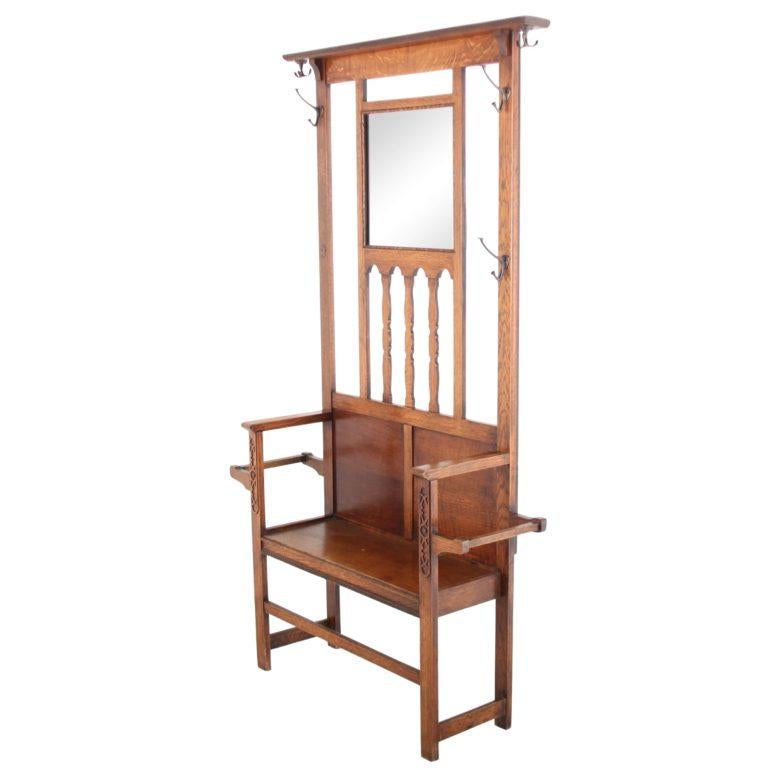 An English oak hallstand from the early 20th century. Complete with mirror, brass hooks, and a seat for donning/doffing boots, shoes, etc. Lovely twisted columns and inset carvings, circa 1920.



 