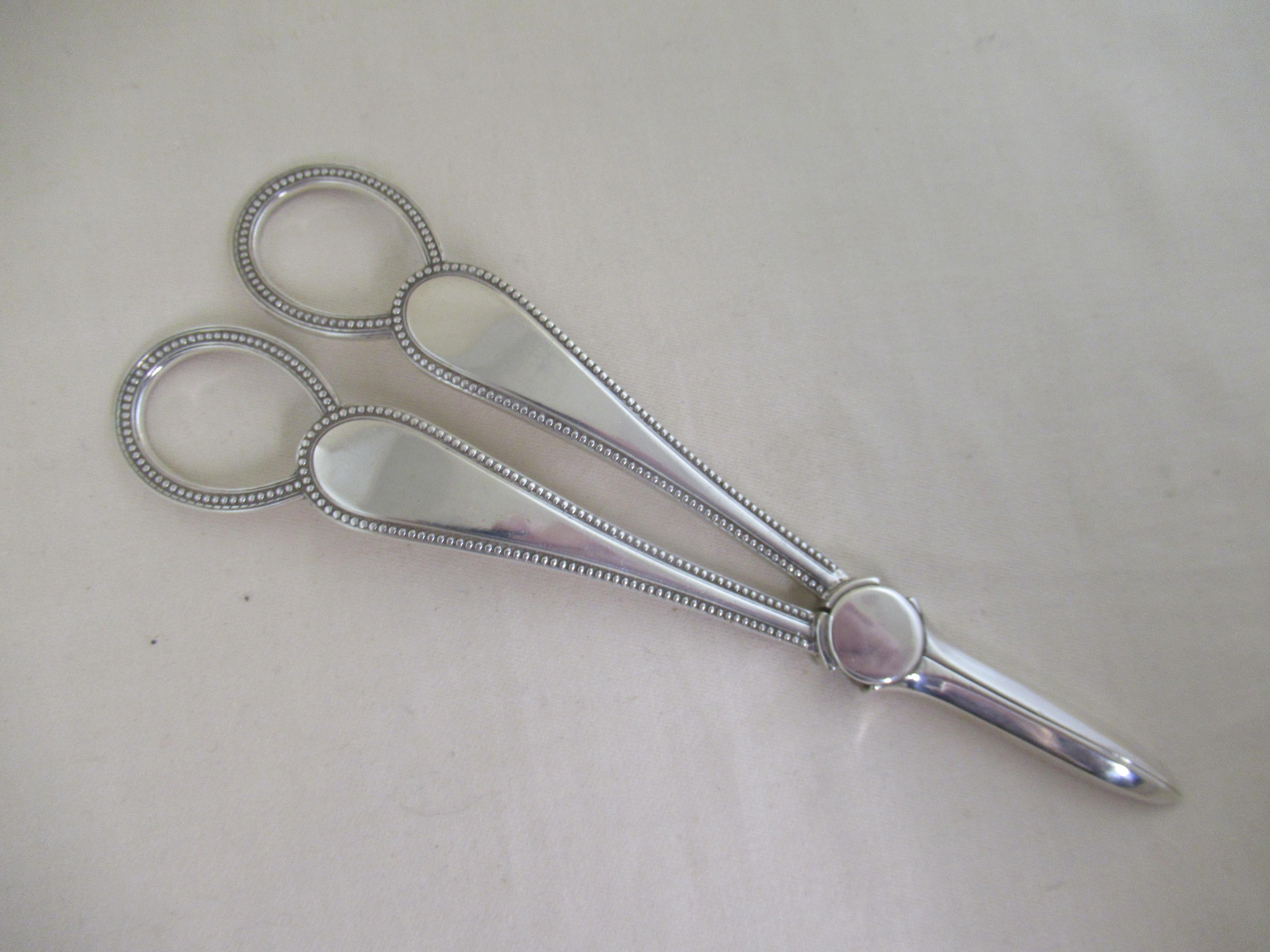 A superb pair of grape scissors or shears in the original box.
Used to cut a bunch of grapes from the vine, but also to grip the cut stem so that the bunch can be lifted down, carefully.

Made in 1897, and with a full set of English hallmarks