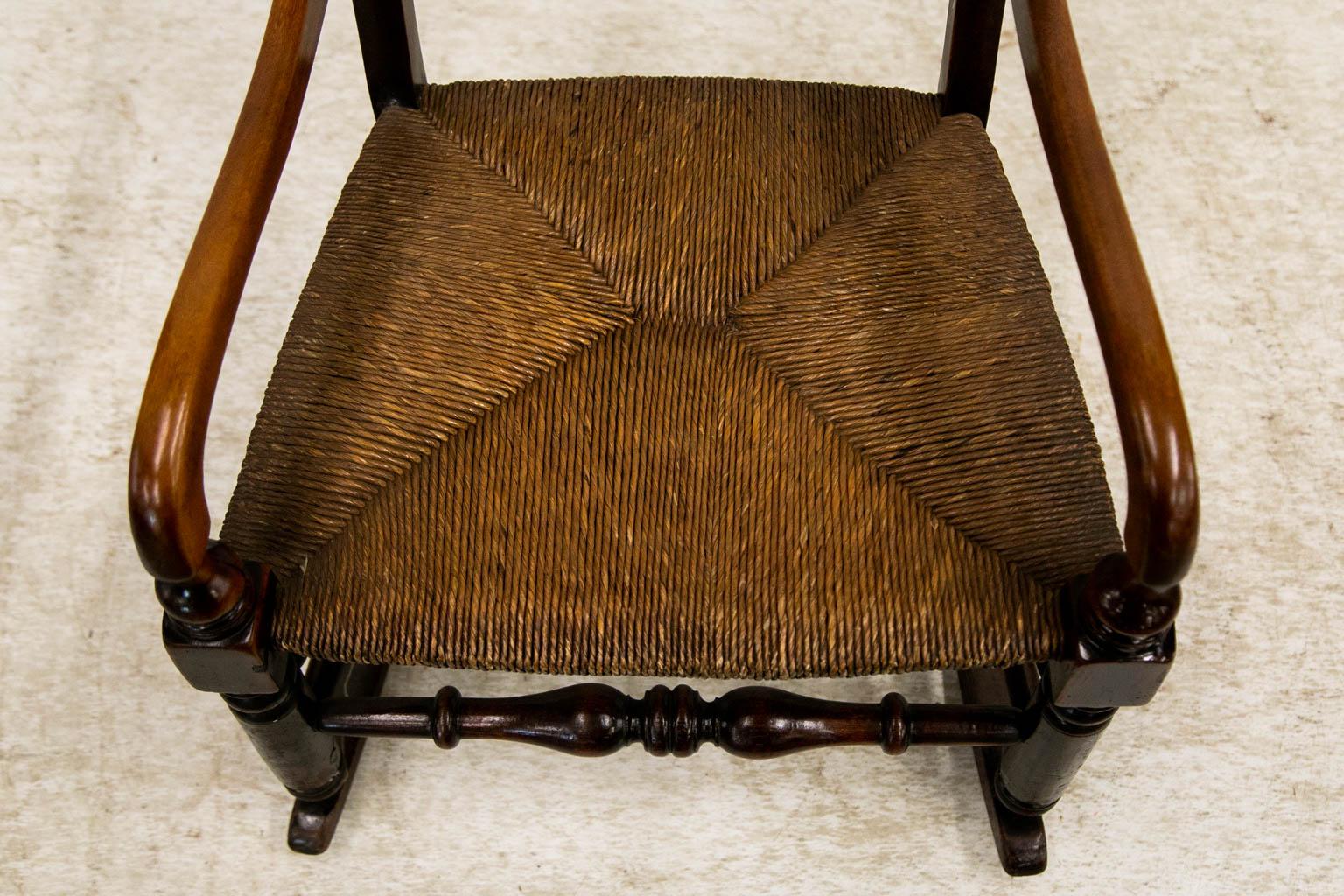 This fruitwood rocking chair has a double spindle gallery backsplat. The original rush seat is in mint condition. The ogee shaped arms are supported by turned legs which are in turn supported by a single turned stretcher in the front and double