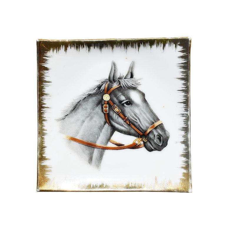 A small square equestrian motif catchall or trinket dish. Decorated with gold around the outer edges, this decorative plate will be fabulous either hanging on a wall or on a coffee table, nightstand, or side table. At the center, painted on a crisp