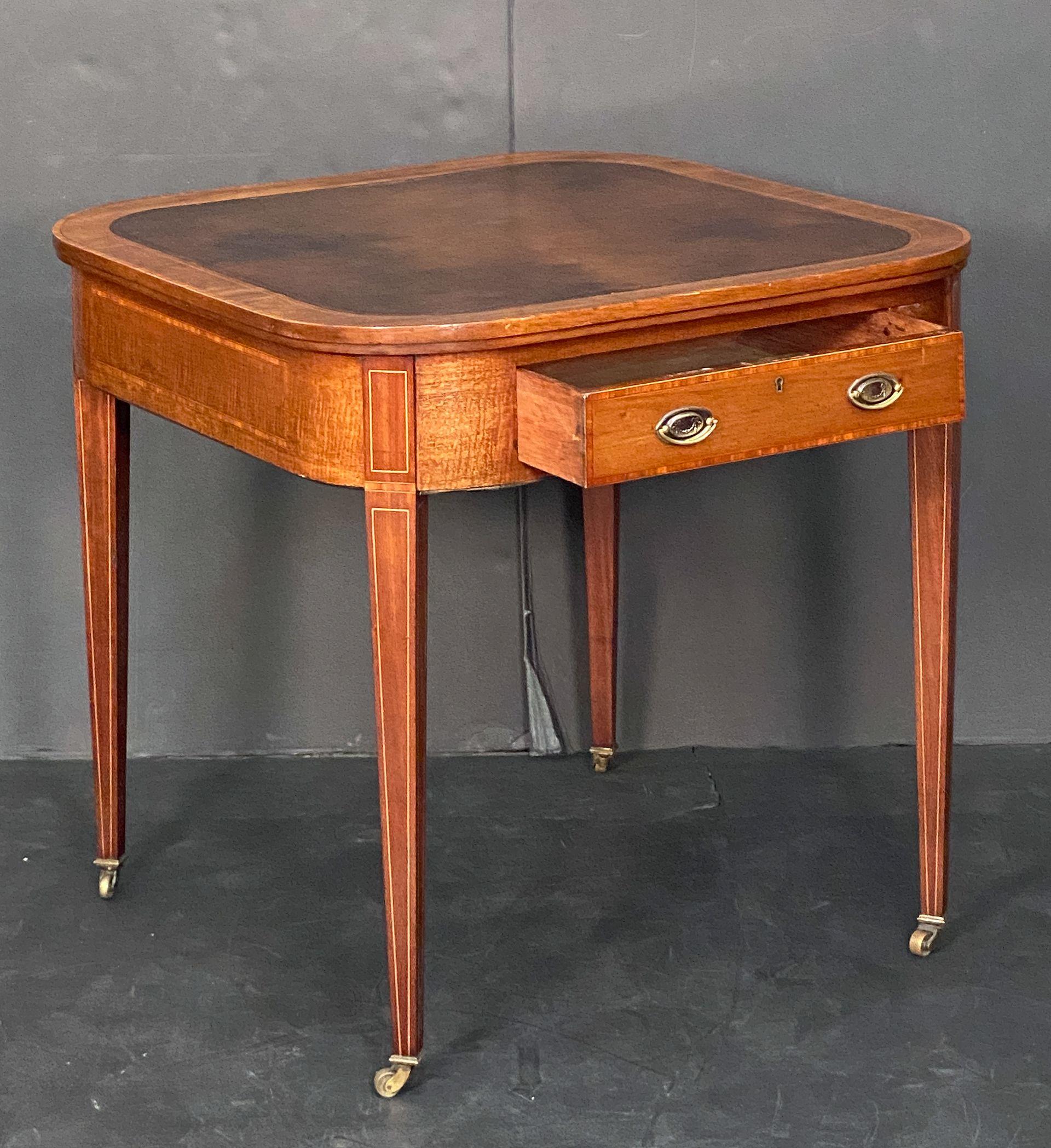 Fina mesa o escritorio inglés de caoba con incrustaciones de la época eduardiana, con tablero de cuero cuadrado repujado, borde moldeado en toda la circunferencia, sobre un friso con dos cajones opuestos -cada cajón con bandas decorativas con