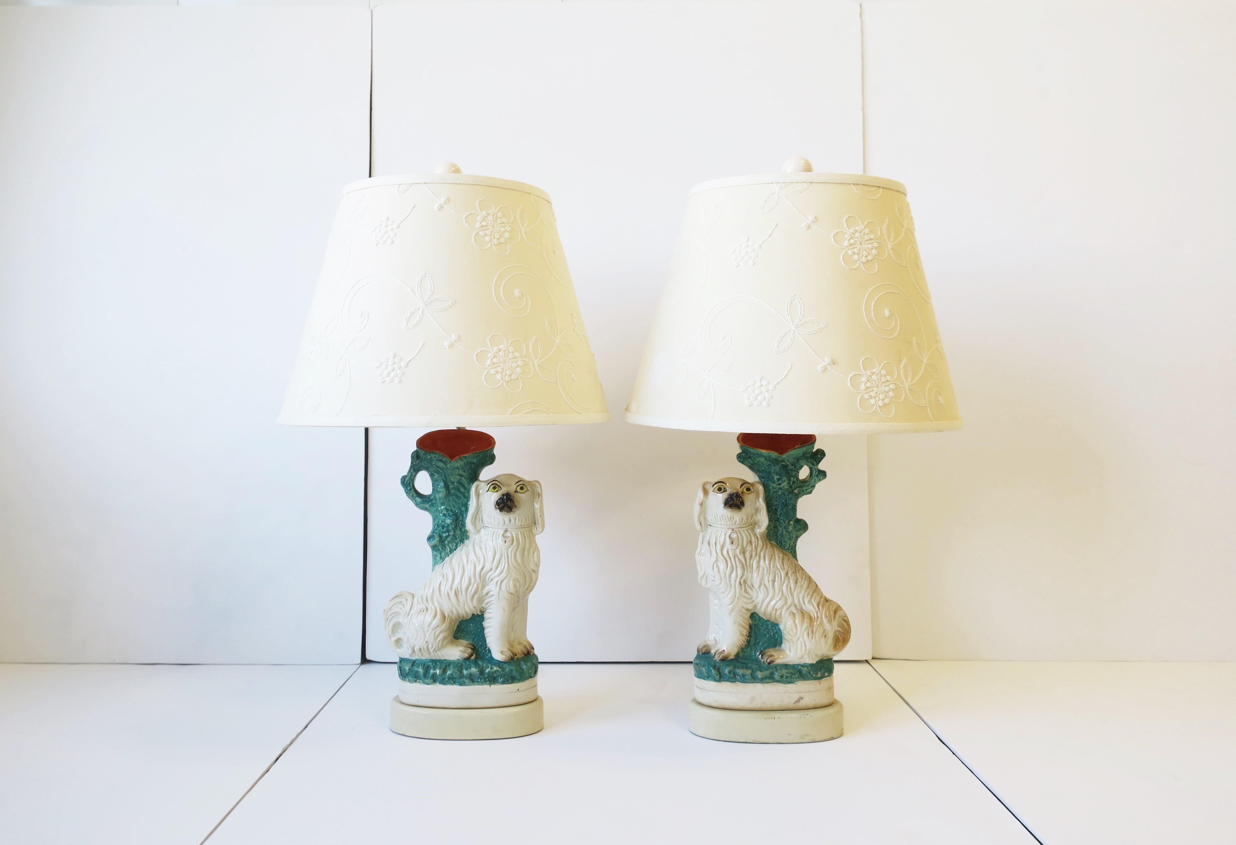 A rare pair of antique English Staffordshire dog and pottery spill vase lamps, circa mid to late-19th century, England. Each lamp represents a white dog with collar and locket, seated against a blue/green and orange spill vase 'tree'. The spill vase