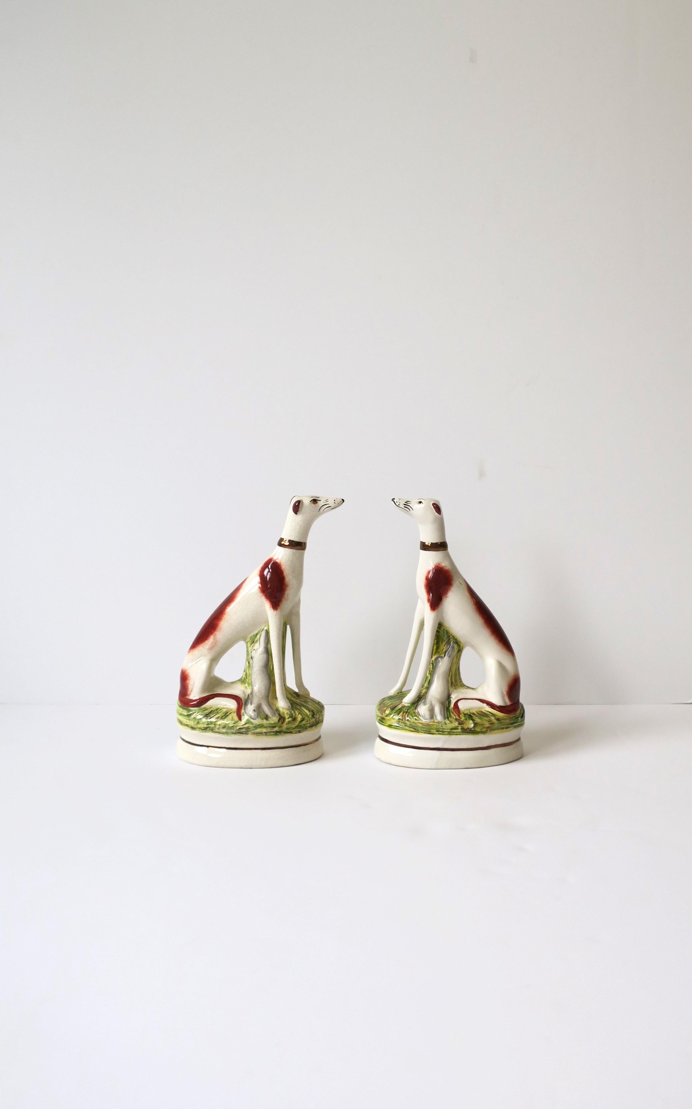 A beautiful regal pair of English Staffordshire dog bookends or decorative objects, circa late-20th century, England. Dogs' have great facial detail and gold neck collars sitting in a garden with their rabbit catch. 

Dimensions: 9.25
