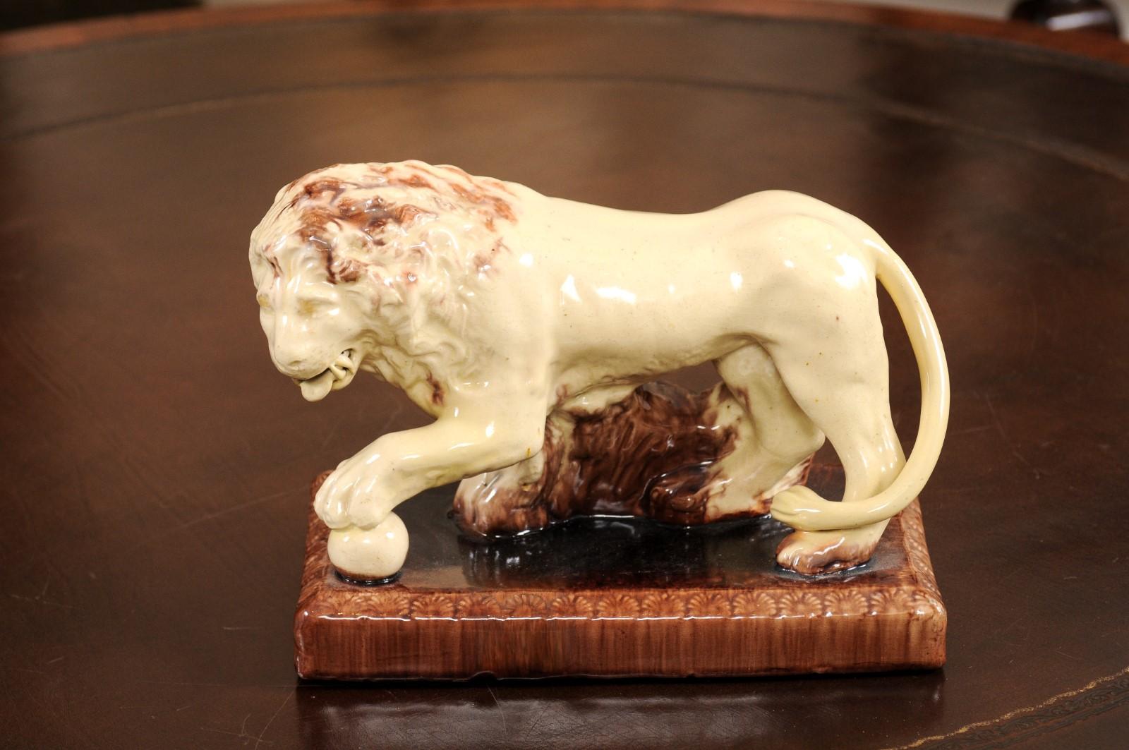 The English 19th century Staffordshire figurine depicting a Medici standing male lion with ball under one paw, looking to one side. 

 