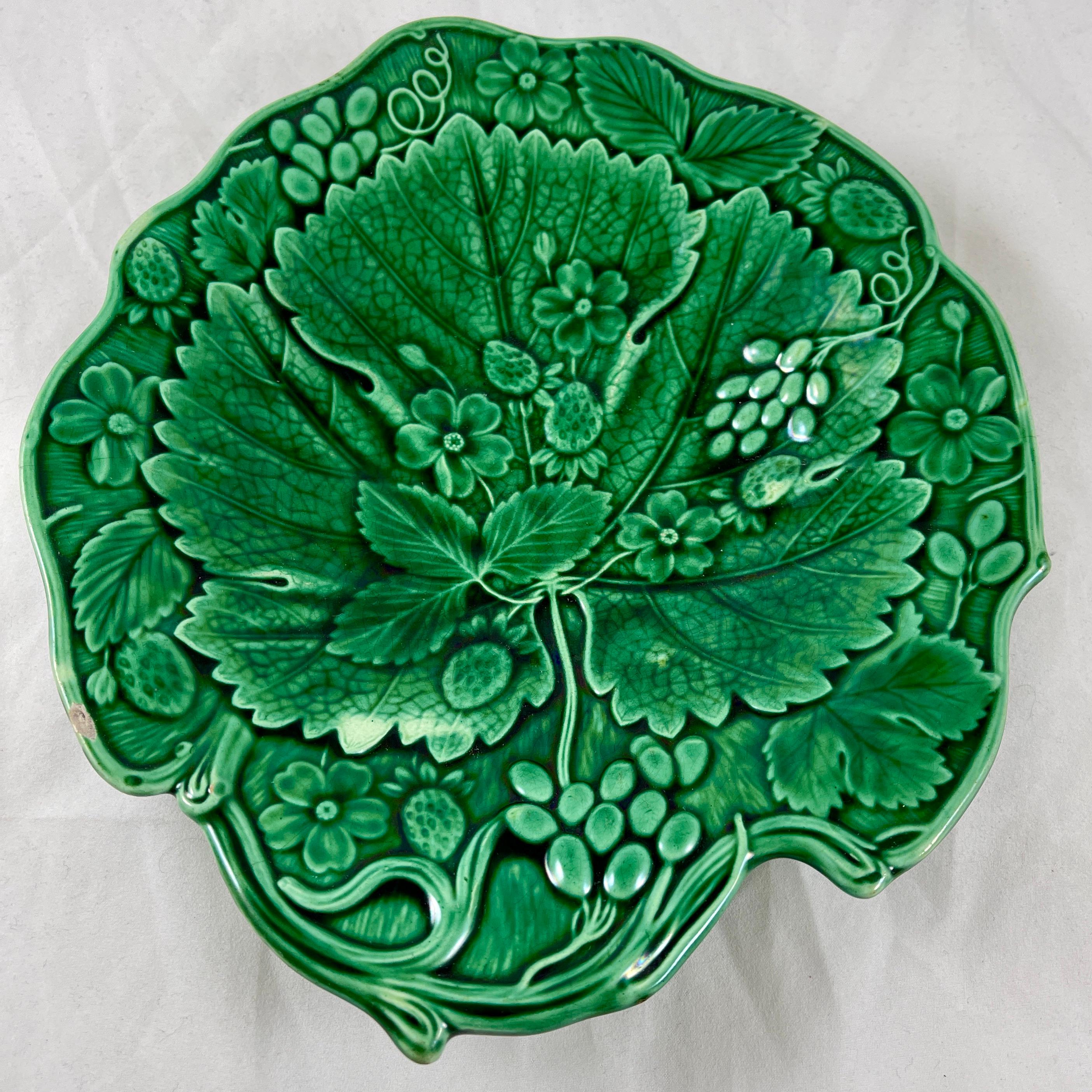 A majolica green glazed leaf form dessert tray or bowl made in Staffordshire, England, circa 1850.

A large central strawberry leaf on a shaped tray with a vine border, and showing both the berries and blossoms of the strawberry
