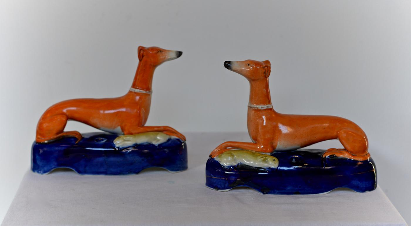 A pair of dashing recumbent whippet quill keeps residing on cobalt glazed bases with paws happily crossed and hares at their sides. The hand painted and glazed figures have been recently deaccessioned from the Colonial Williamsburg Foundation and as