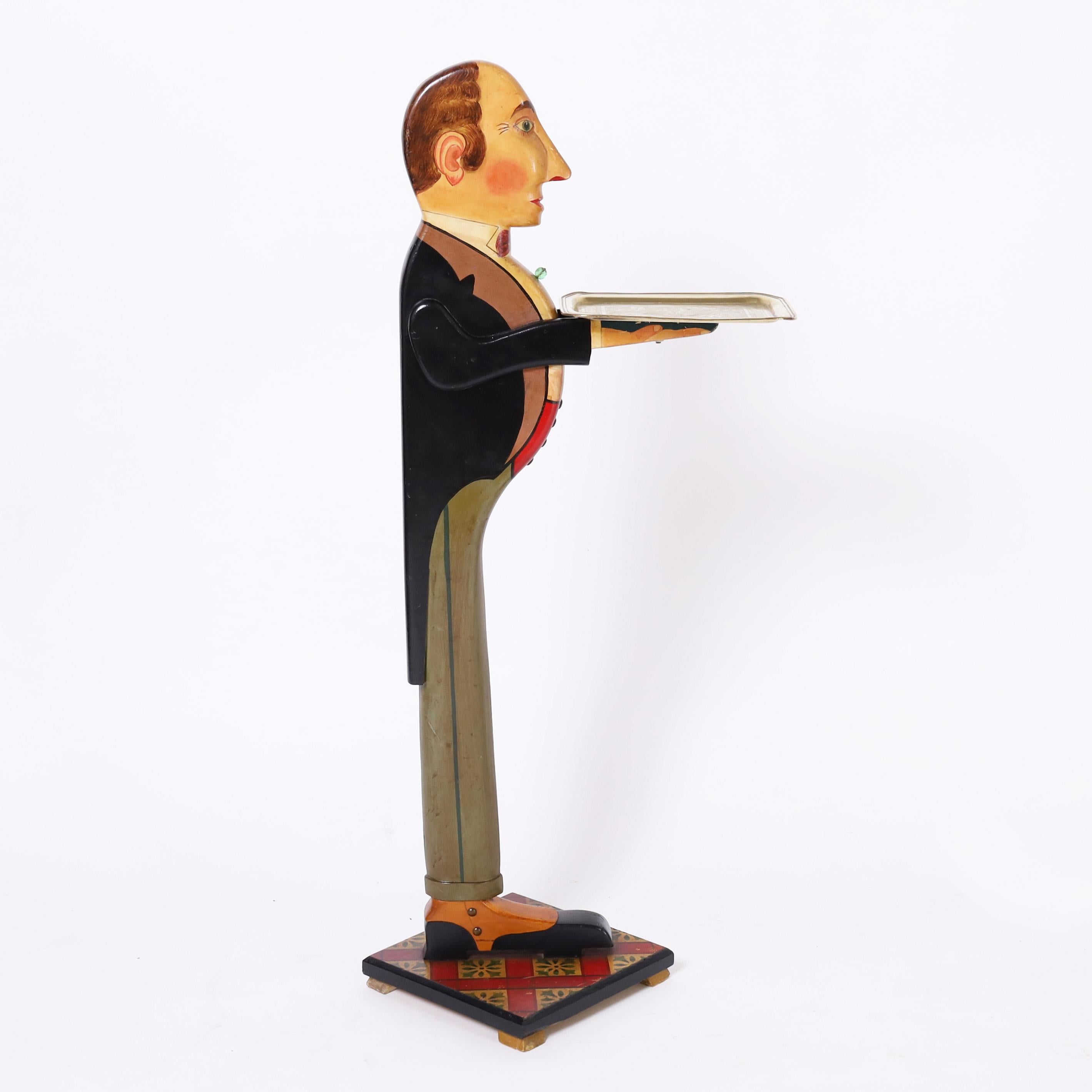Dapper art deco standing butler with brass tray crafted in hardwood and paint decorated with cliched high collar, boutonnieres, tails and spats, faithfully ready to serve. 