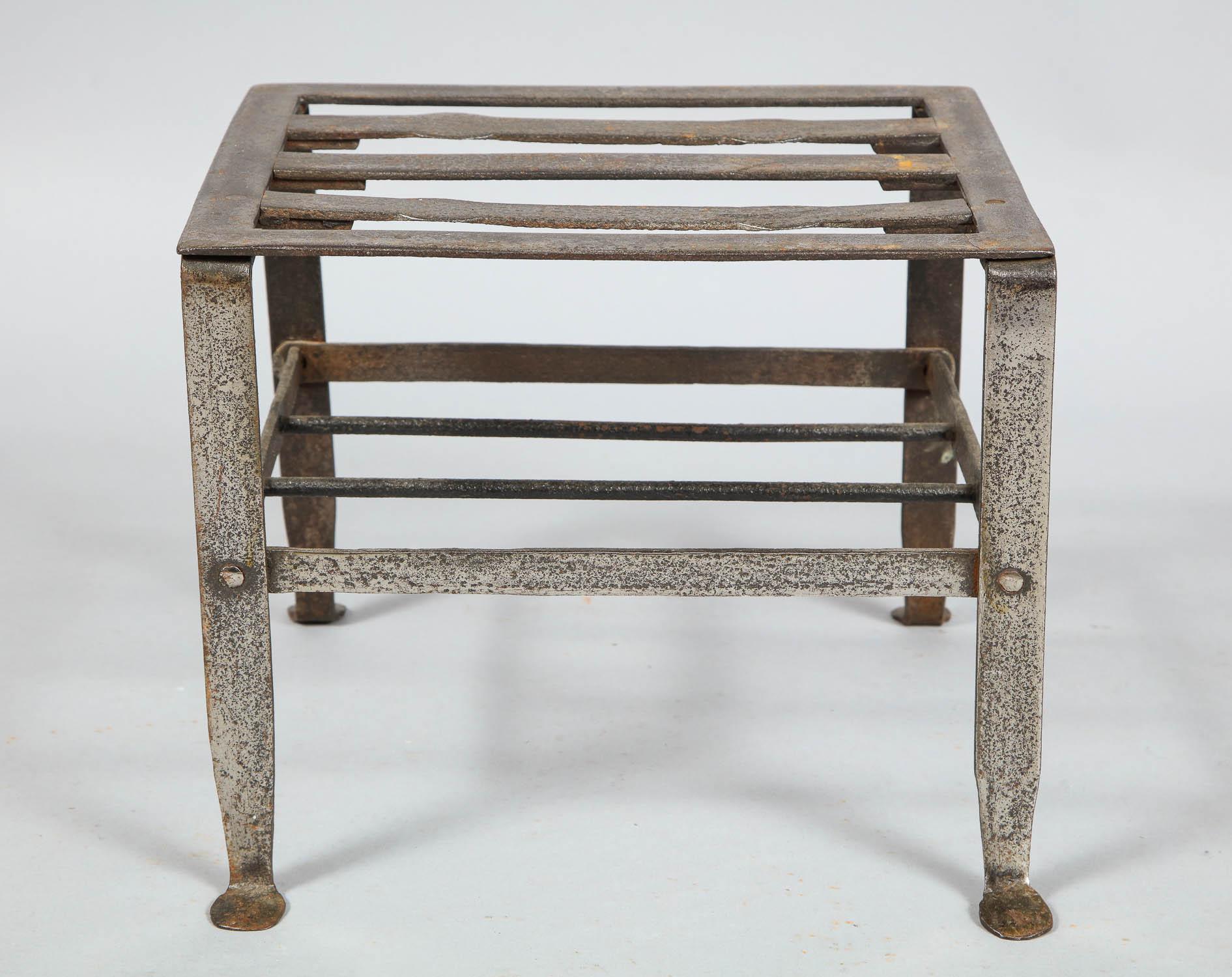 Good early 19th century steel footman or trivet, having a slatted top over four flattened legs joined by peened stretchers and ending in penny feet, the whole with nicely pitted and burnished surface, great as a side table next to a club chair.