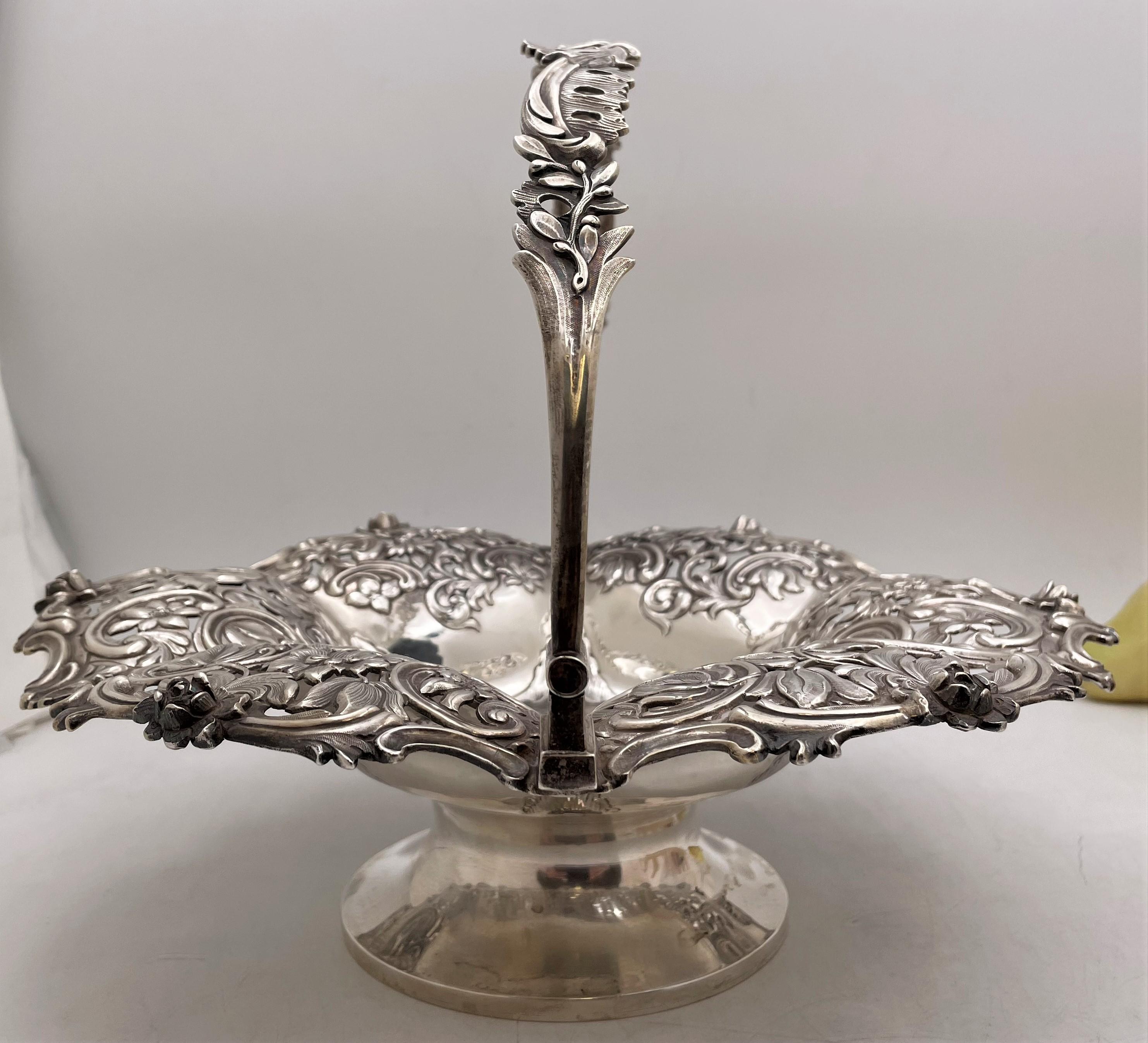 English sterling silver basket or bowl from 1841, designed an enchanting border with raised scrolls, leaves and flowers and standing on a base. It measures 10 3/4'' in height with the handle up (4 1/4'' without) by 12 1/2'' in diameter, weighs 31.5