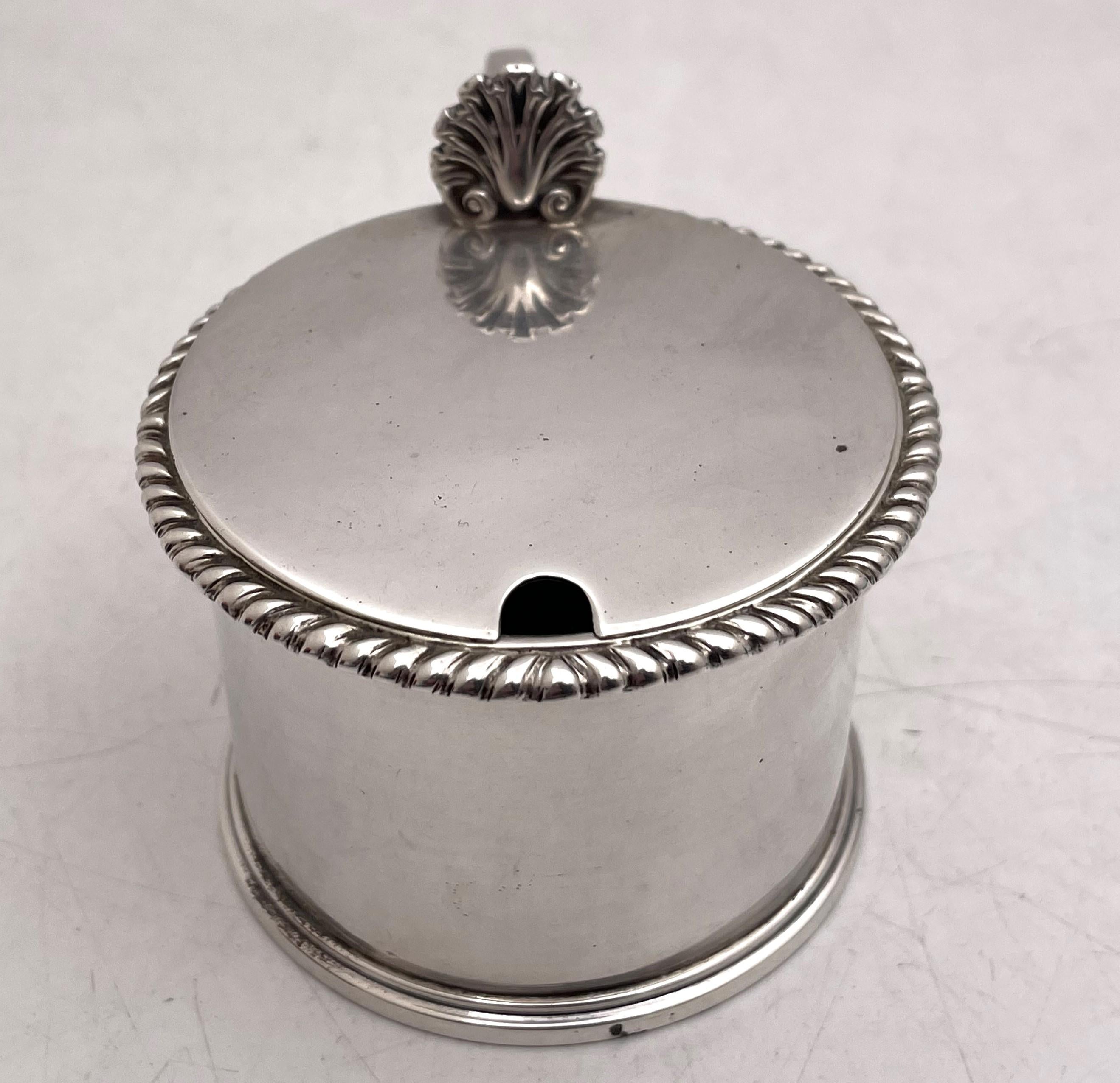 English sterling silver Victorian mustard pot from 1890 with a gadrooned rim, sold with a cobalt glass liner and sterling silver spoon. It measures 3 7/8'' from handle to spout by 2 3/4'' in height. The spoon measures 3 1/2'' in length. Hallmarks