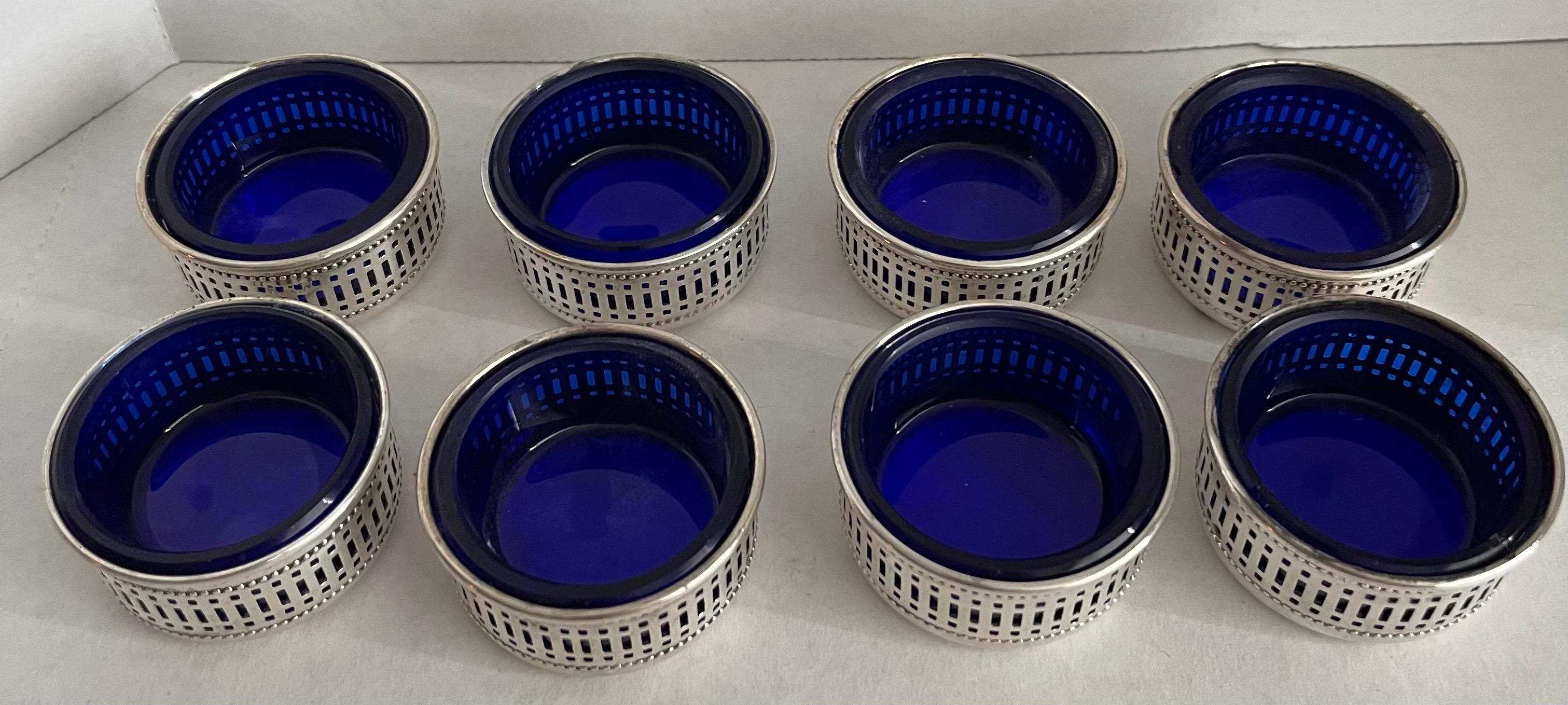 Set of 8 English sterling silver salt cellars with cobalt blue glass liners. Reticulated detailing. Stamped “sterling” on the underside. No makers mark or hallmarks.