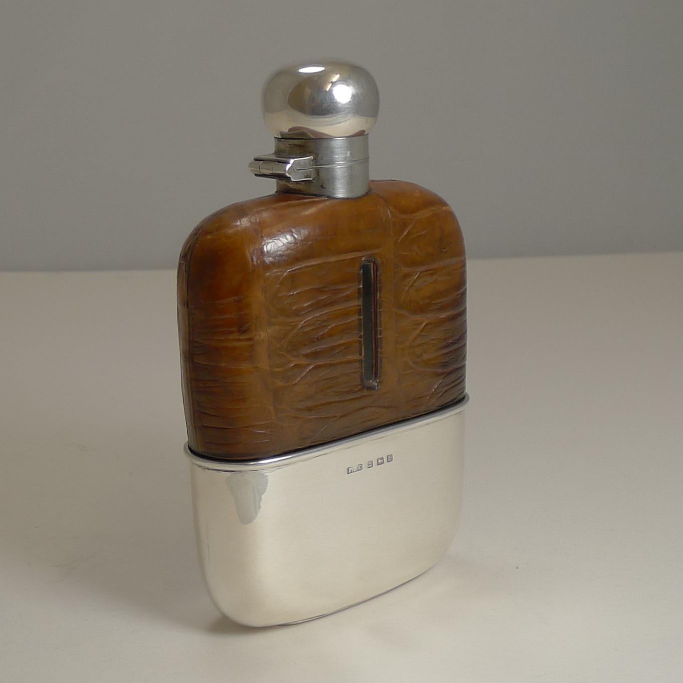 A handsome English sterling silver hip or liquor flask made from sterling silver and the upper half wrapped in Crocodile skin with a lovely cognac color with a good patina.

The collar and hinged lid are made from sterling silver as is the