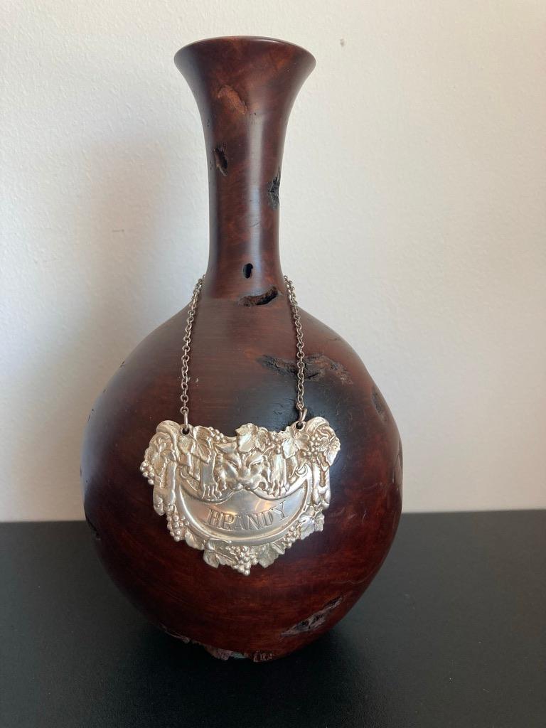Mid 20th century English silver hanging label for a brandy bottle or decanter. Shown with a lion skin holding the cartouche with mouth and paws, surrounded by grape leaves and clusters of grapes. Beautifully cast in the 17th century Baroque style.