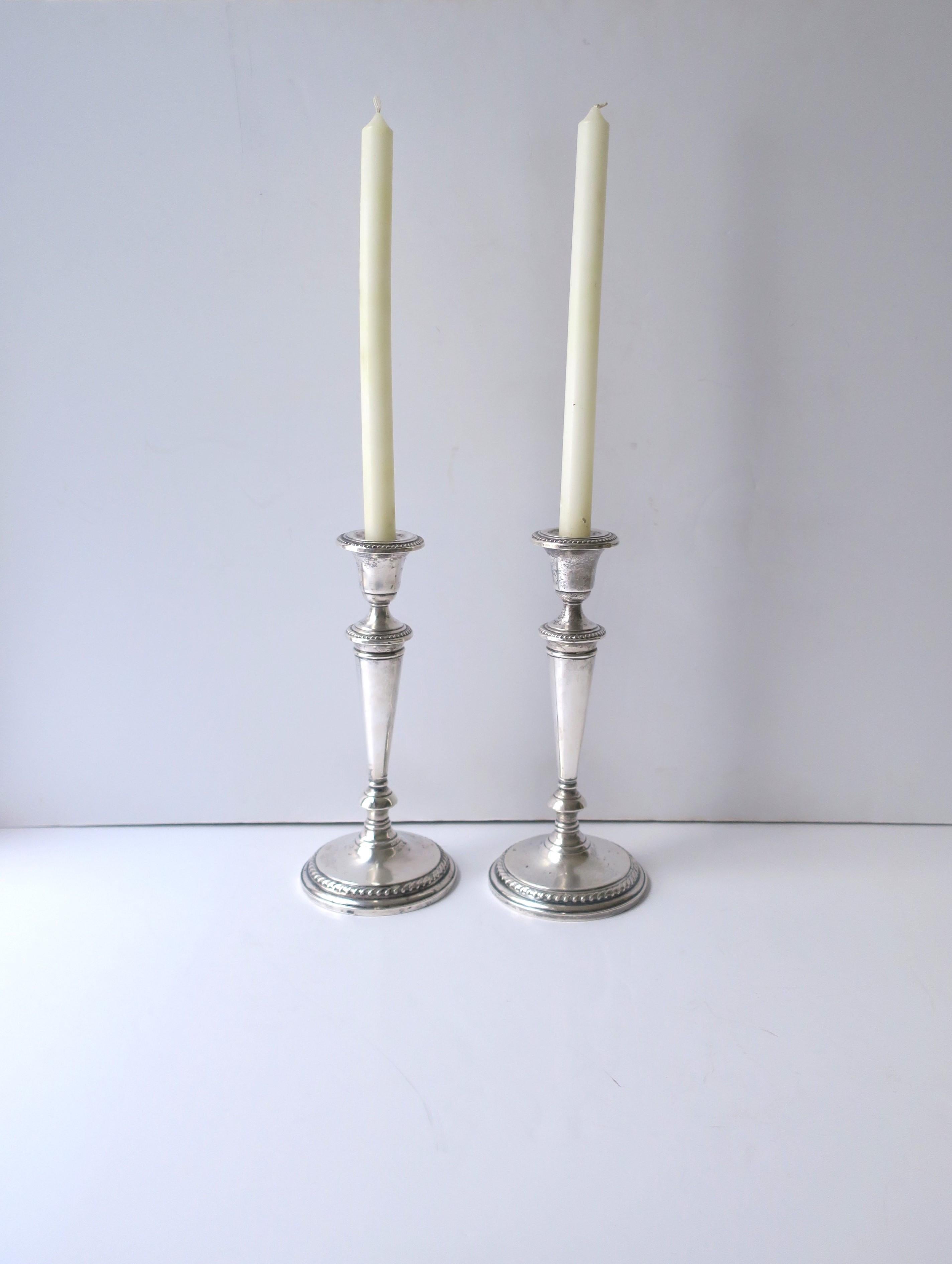 An English pair (2) of sterling silver candlestick holders, circa early to mid-20th century, England. A beautiful set with decorated candle cup supported by a conical shaft on a circular decorative edge base. With marks' mark and sterling mark on