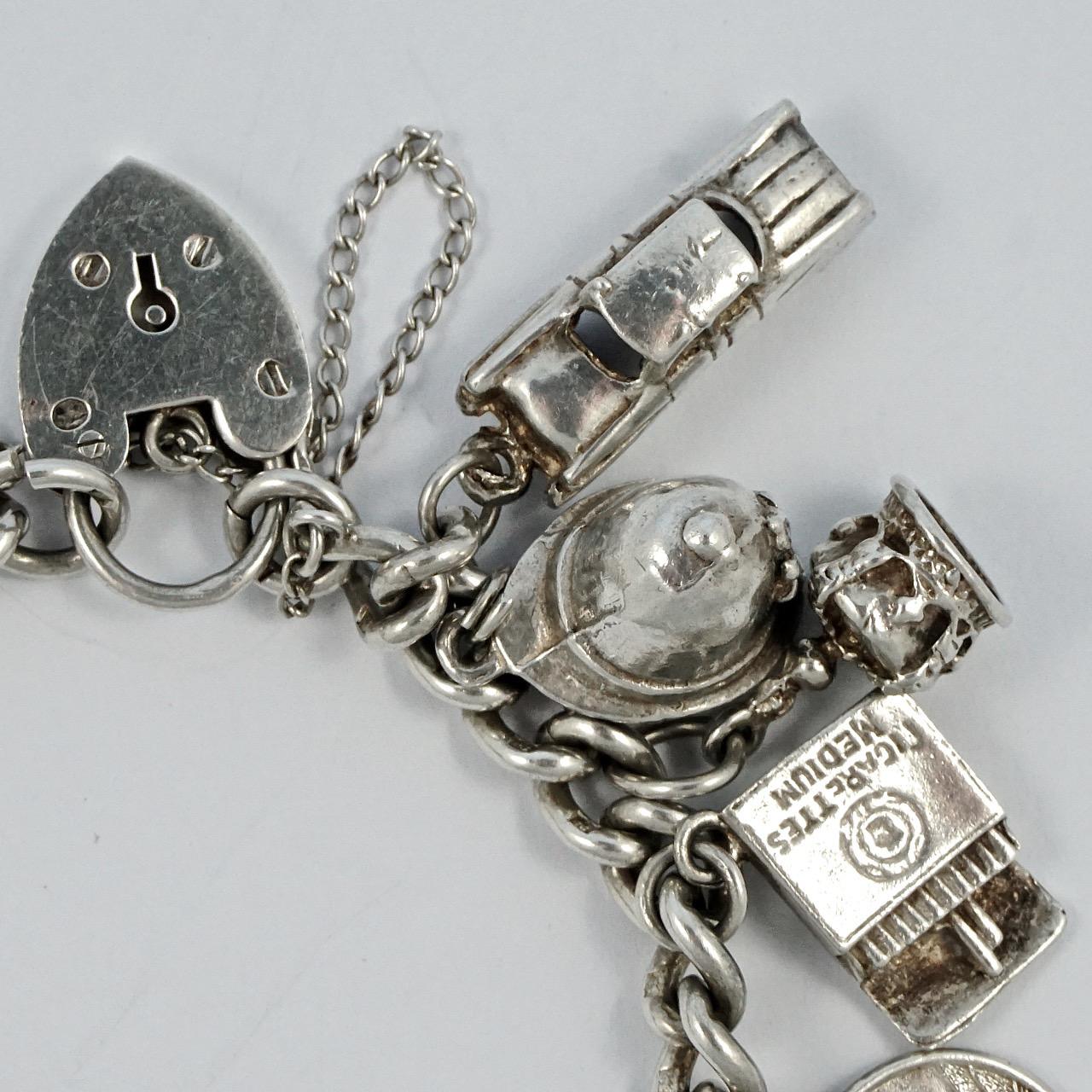 Delightful English sterling silver charm bracelet with a heart lock and chain. There are nineteen charms: a car, police helmet, crown, cigarettes, St. Christopher, coffee pot, cash register, sundial, shoes, nude lady holding flowers, lion's head,