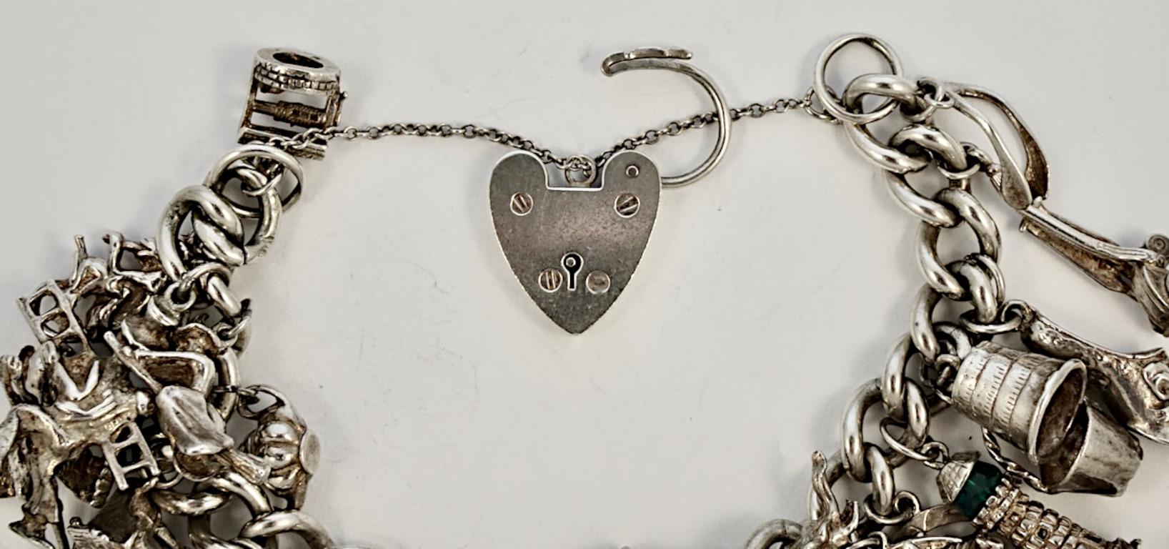 Delightful English sterling silver charm bracelet with a heart lock and chain.

There are twenty seven charms: wishbone, hoover, thimble, shoe, champagne in an ice bucket, lighthouse, horse and horseshoe, eros, cat with ball, elephant, cat with