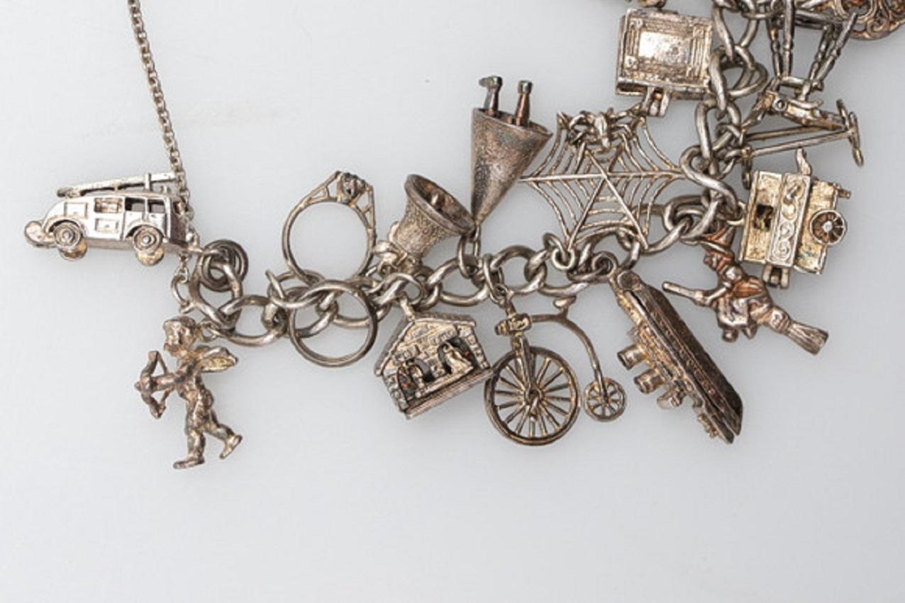 Open curb link bracelet with heart padlock clasp hung a variety of charms, including, a fire engine, motorcycle, trolley bus, doctor’s bag, dunce hat, barrel organ and an engagement ring with a jewel on top. A Lovely English sterling silver