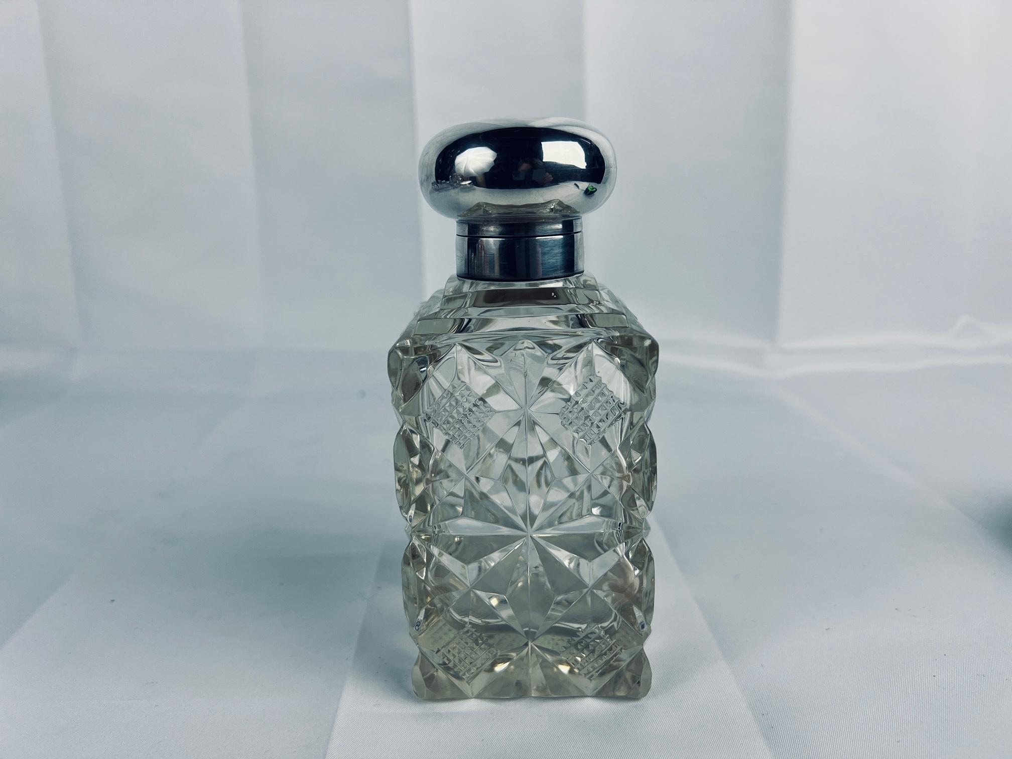 This elegant vanity jar, crafted in the early 20th century, exemplifies the refined aesthetics and exceptional craftsmanship of English decorative arts. The jar features a finely cut glass body, adorned with intricate patterns that catch and refract