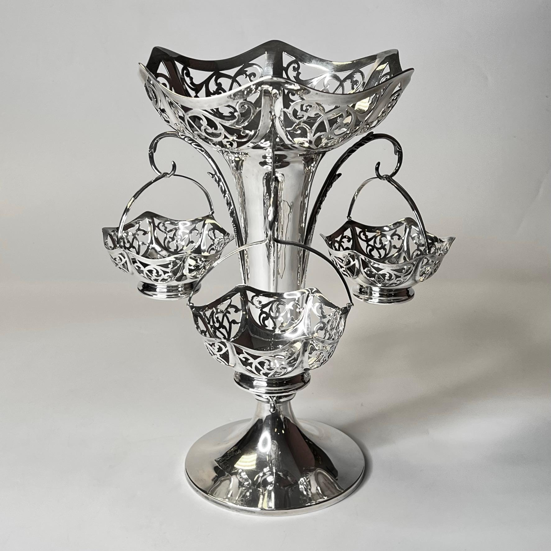 Our exceptional sterling silver centerpiece from the Art Nouveau and Arts and Crafts period comes from the London firm of Goldsmiths & Silversmiths Company Ltd. It features a central vase with reticulated rim of organic scrolls and three handled