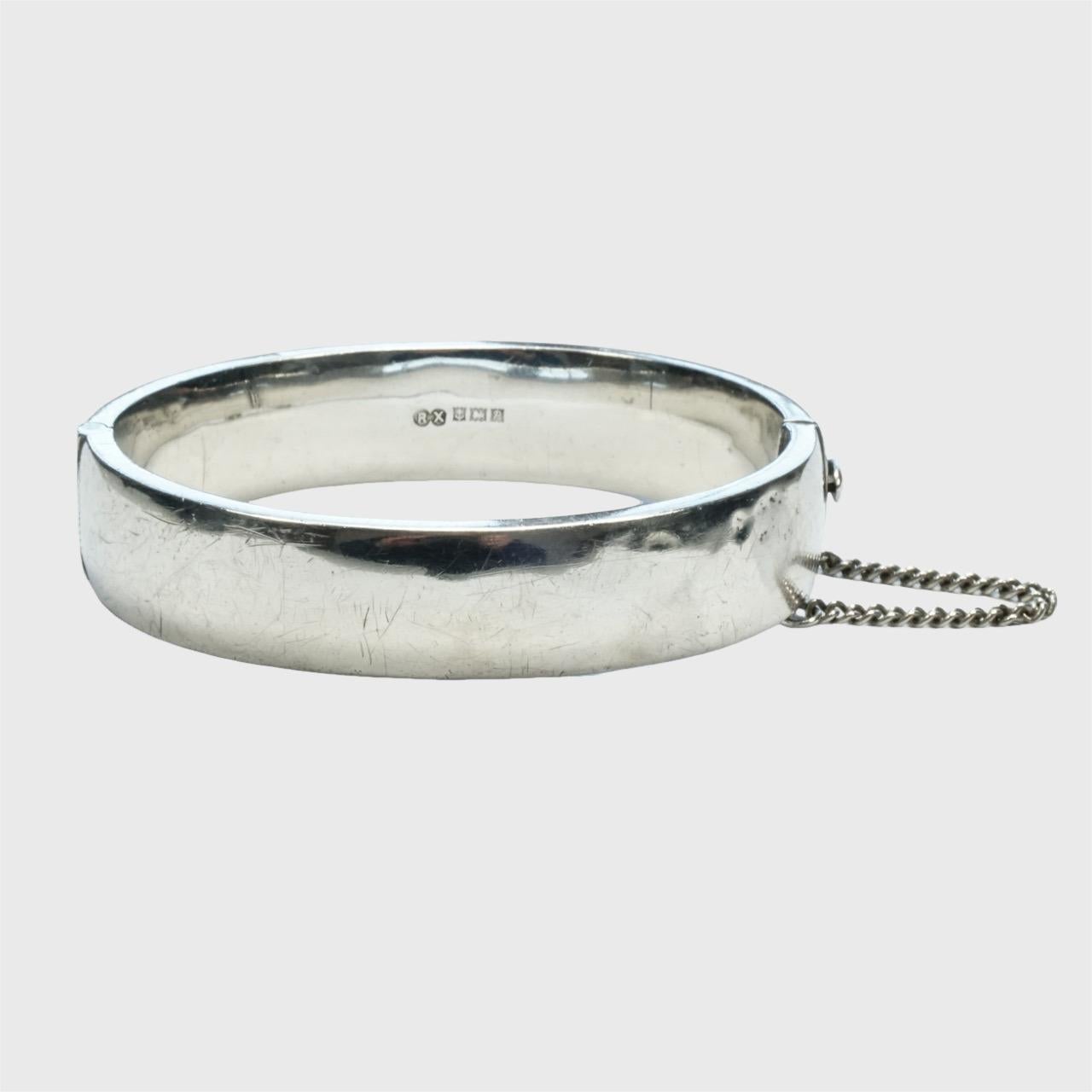Lovely sterling silver engraved flower bangle bracelet with a safety chain. The engraving is on the front, the back is plain. 

The inside measurements are 6.8 cm / 2.6 inches by 6 cm / 2.3 inches, and the width is 1.5 cm / .6 inch.

The bracelet is