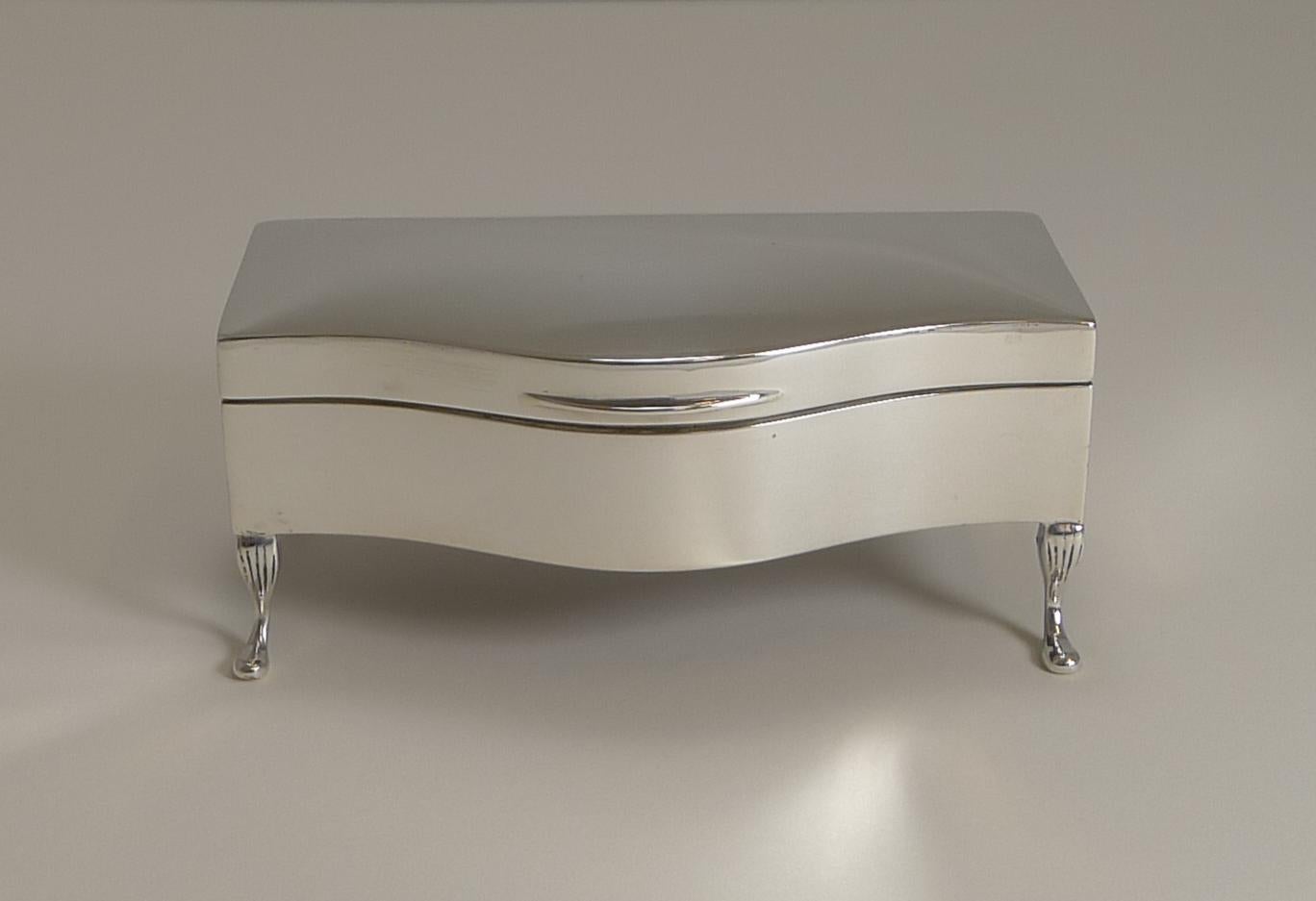 A truly elegant jewellery or ring box and in such superb condition. Made from English sterling silver, the box with its shaped front, stands on four stylish cabriole legs.

The lid fits well and once opened reveals a superb clean lined interior
