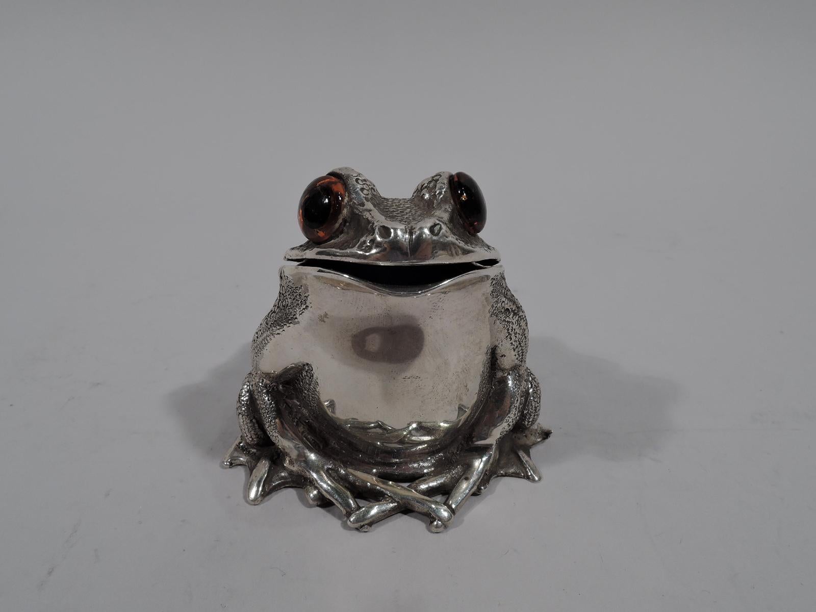 Novelty sterling silver mustard pot. Made by Richard Comyns in London in 1969. A squatting reptile with legs gathered close to body. Scaly back, smooth breast, and intense glass exophthalmic eyes. Head hinged. Interior has cylindrical well with