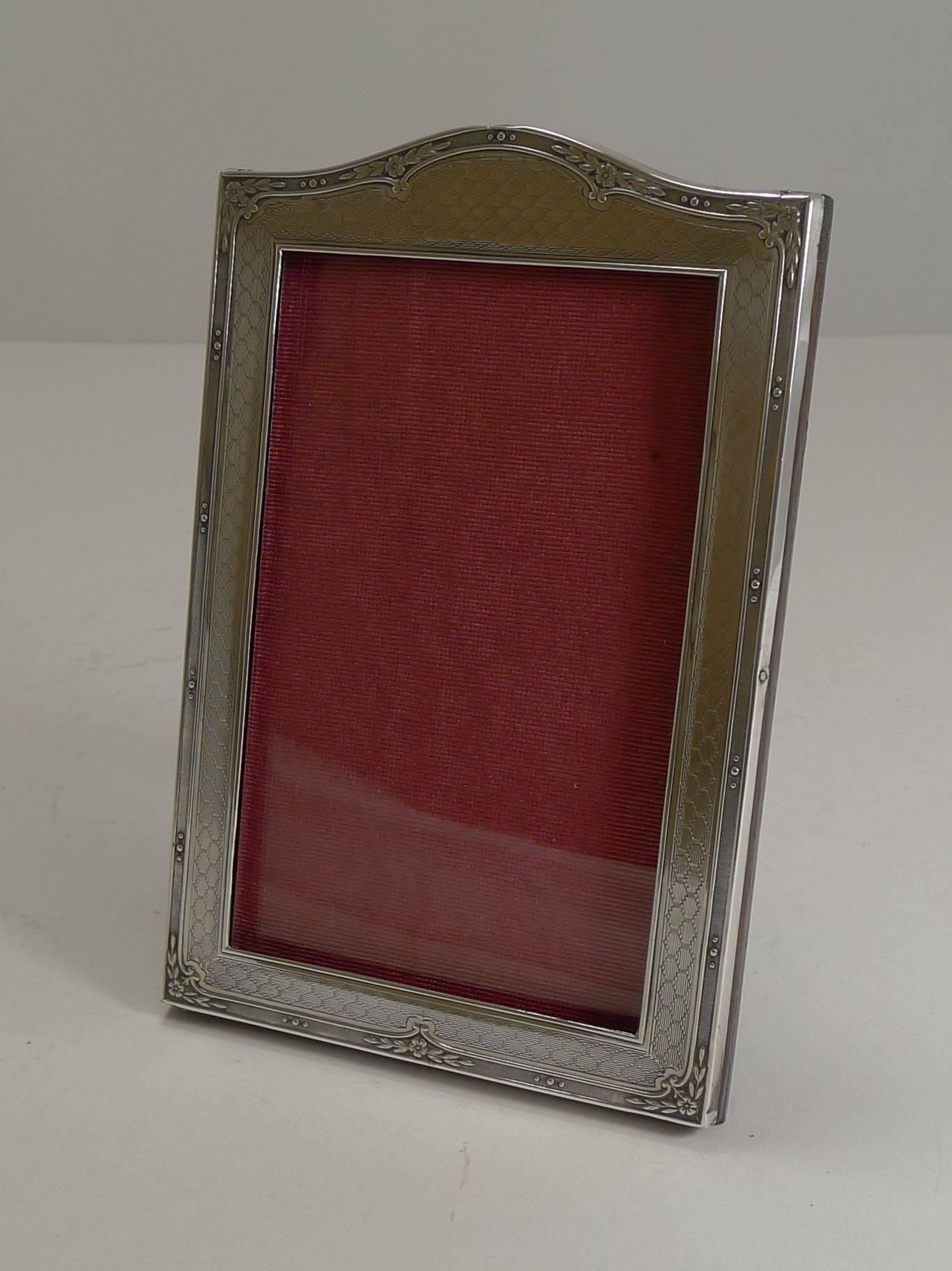 Pretty as a picture, this lovely English photograph frame is made from English sterling silver with a solid English oak backing complete with a folding easel back stand.

The silver incorporates engine turned decoration and pretty floral and