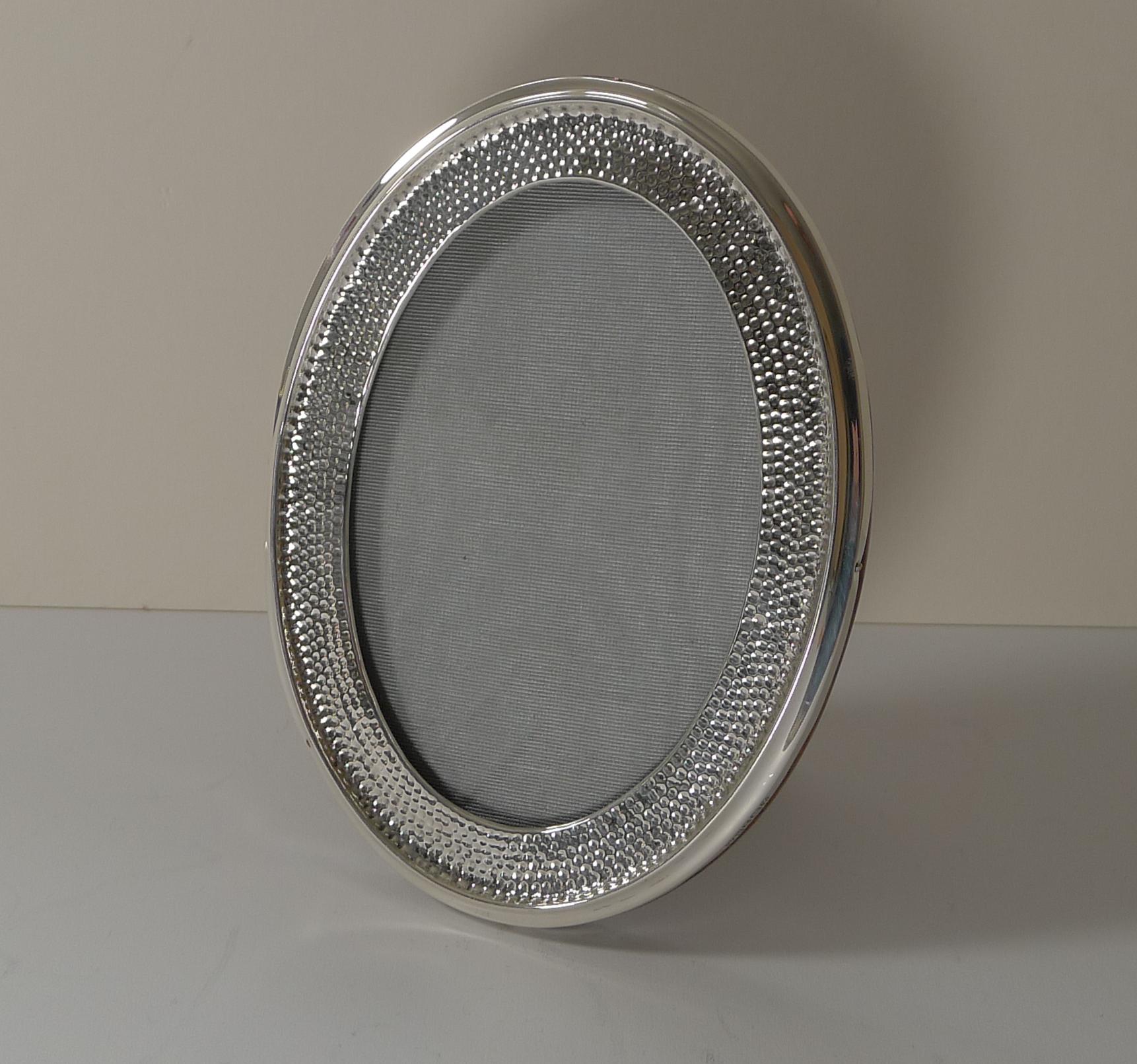 A stunning photograph frame, simple yet highly decorative. Of ovoid form, the silver with hammered decoration, when placed in the right light, it almost looks diamond studded!

The back is made from solid English oak with a folding easel Stand.