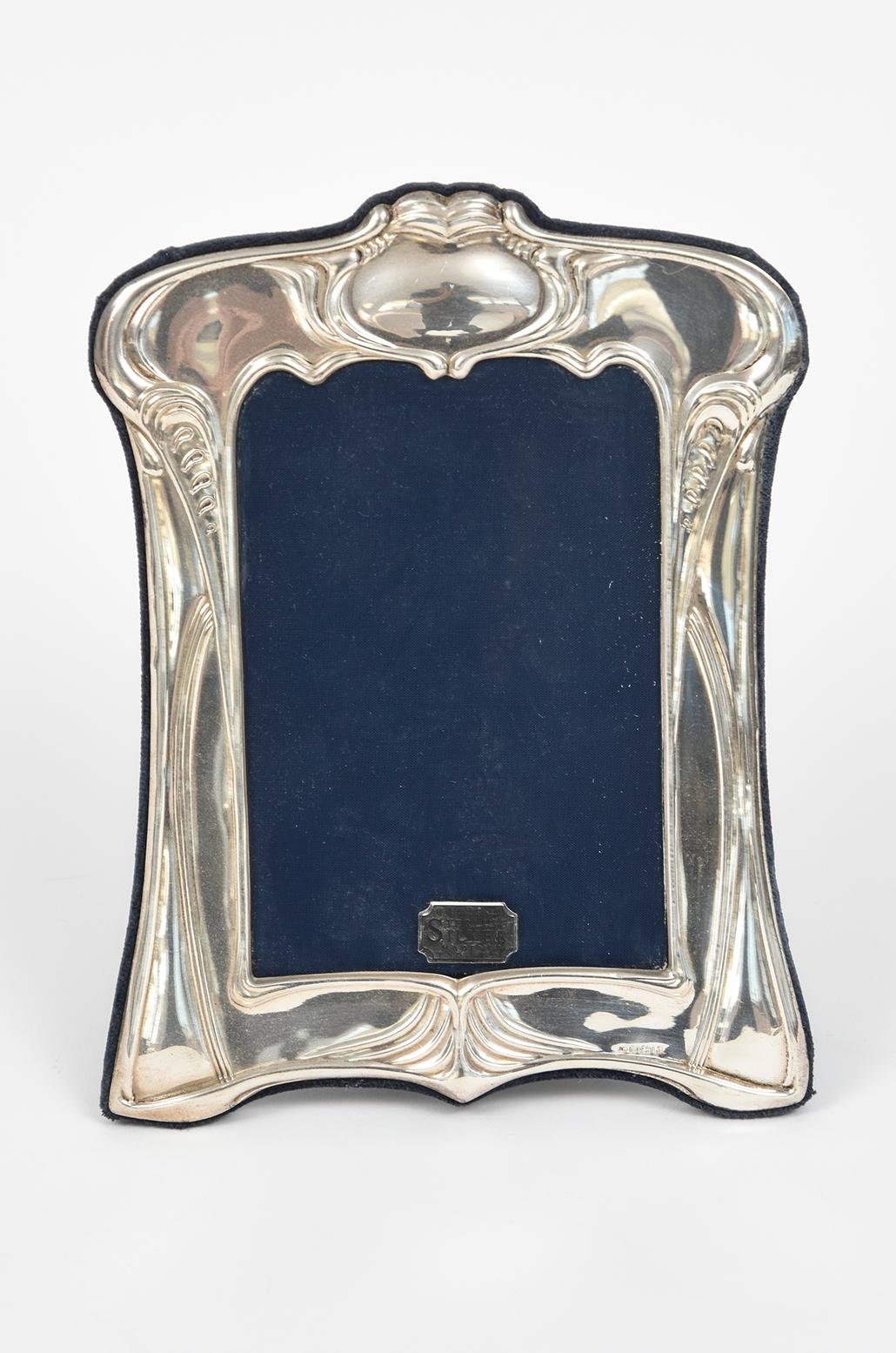 Cornice per foto in argento sterling realizzata da Ron Carr Ltd. Sheffield.  La cornice presenta un disegno a fogliame ornato e una gamba di sostegno nera. 
Punzoni impressi in basso a destra: Marchio Ron Carr 