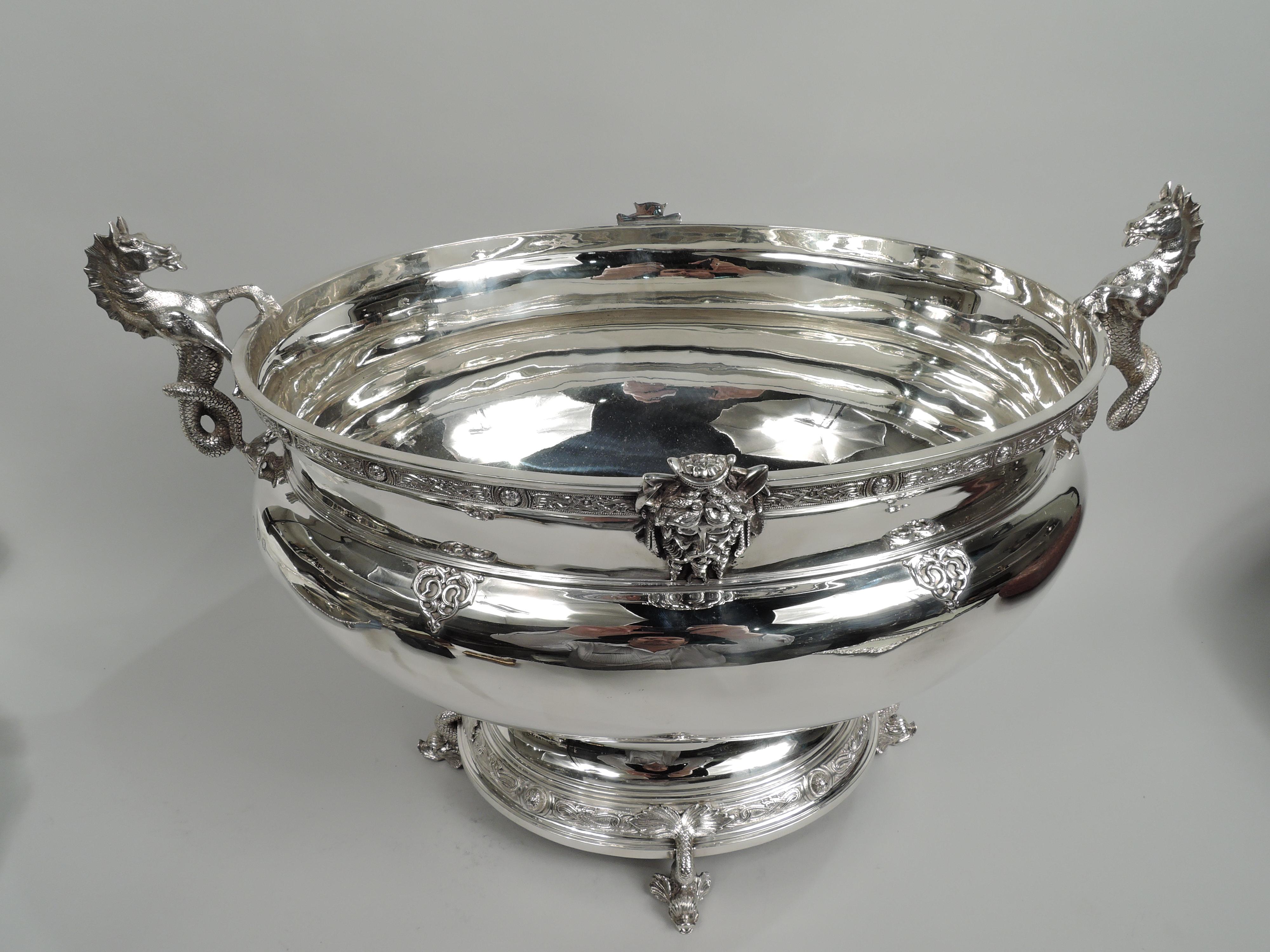 George V sterling silver wine cooler. Made by Reid & Sons in Newcastle on Tyne in 1930.Curved and tapering oval bowl with straight and inset neck. Cast Neptune heads applied to rim and strapwork scrolls applied to shoulder. Seahorse end handles