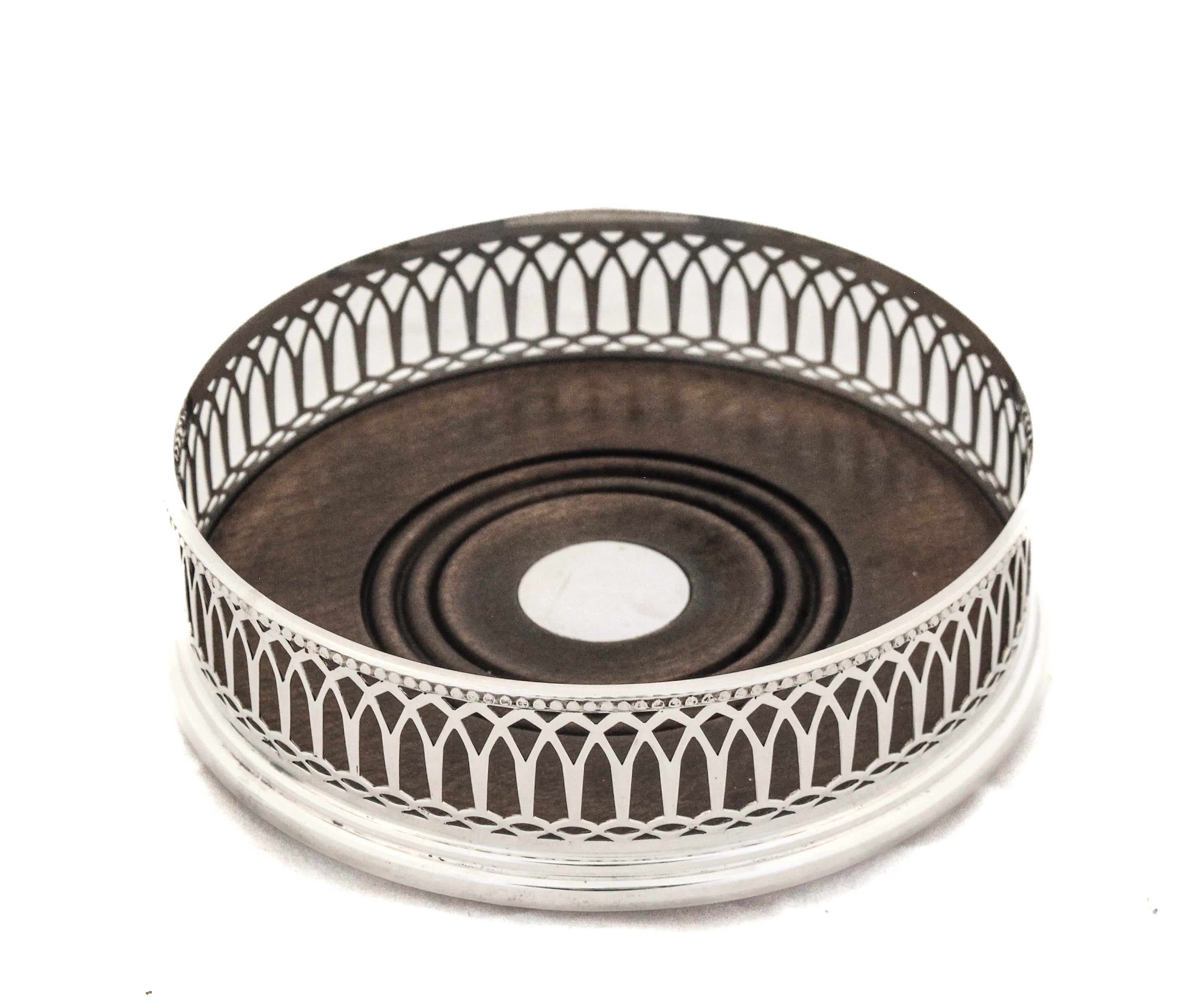 Proudly offering an English sterling silver wine coaster.  The sterling silver border has a reticulated design going all around while the interior wood has been restrained in a deep rich walnut brown finish with a sterling silver medallion in the