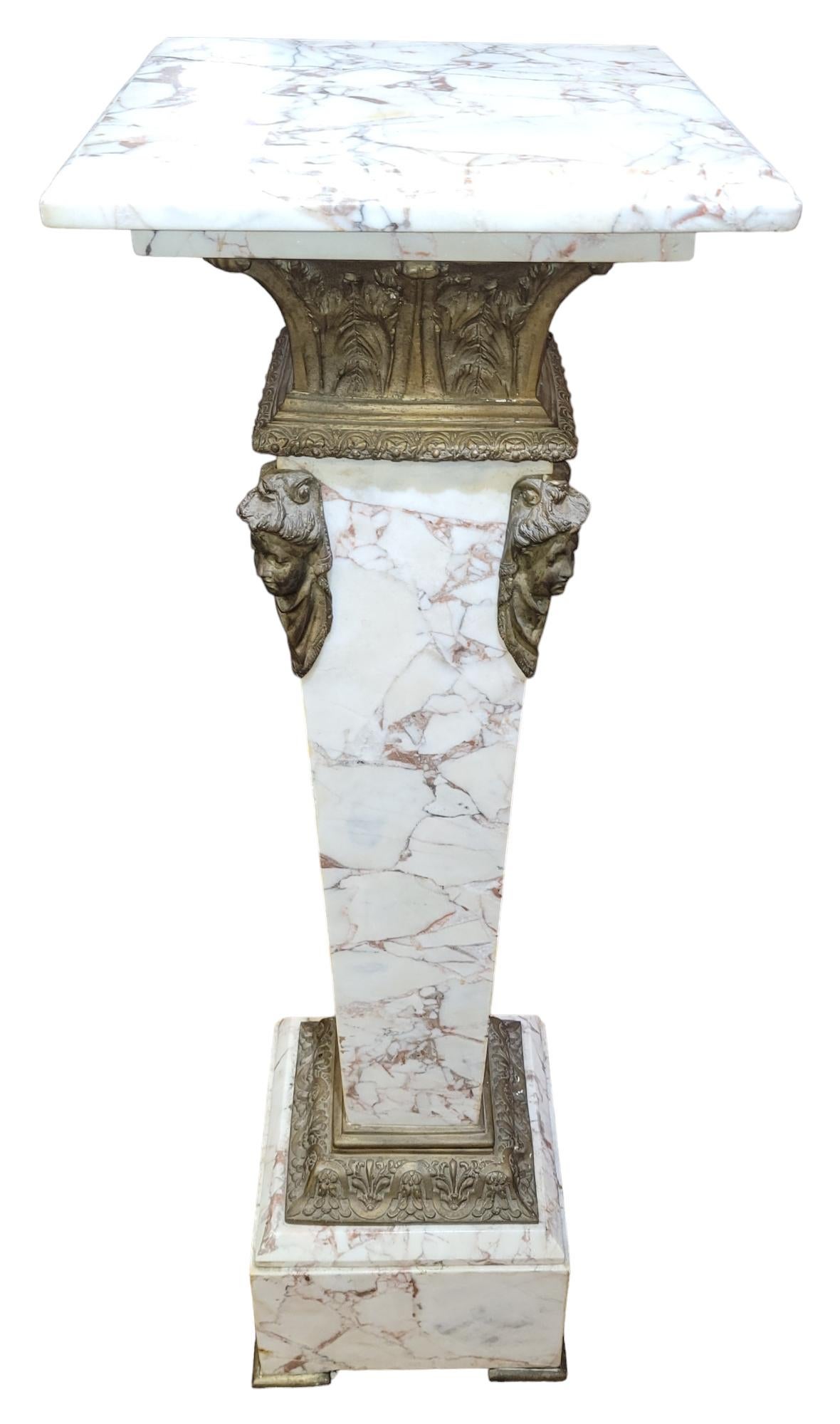 English Style  Marble And Bronze Stand with wonderful bronze corner accents. The base has brass feet, just above the base there is brass accent leading to the stem up to the brass faces. There is a brass neck  leading to the variegated marble top.