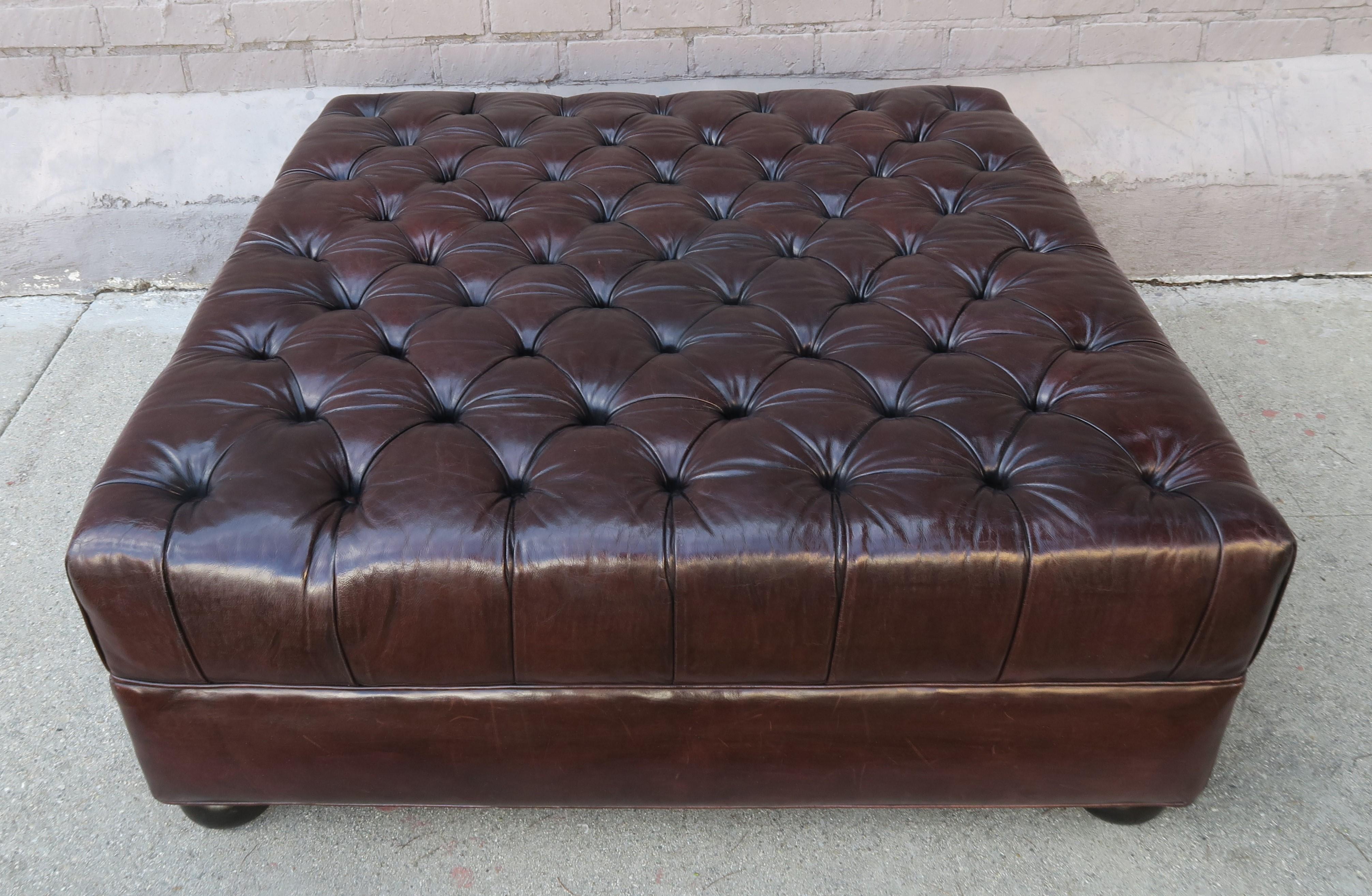 Monumental scale rich chocolate brown colored English style leather tufted square shaped ottoman with bun feet. The white mark is merely a reflection, the piece is all brown.