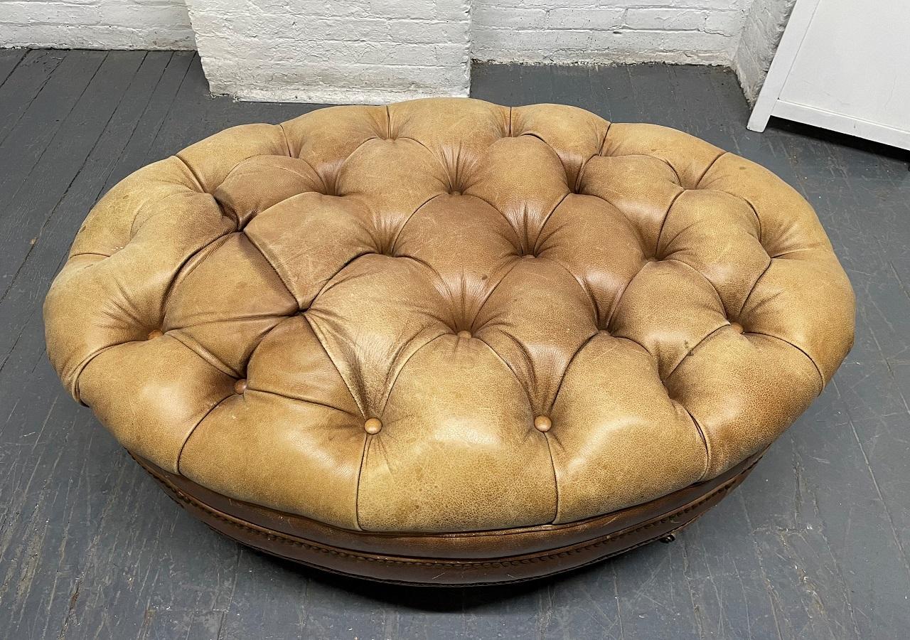English style tufted leather oval shaped bench. The bench also has brass studded trim with wood and brass casters.