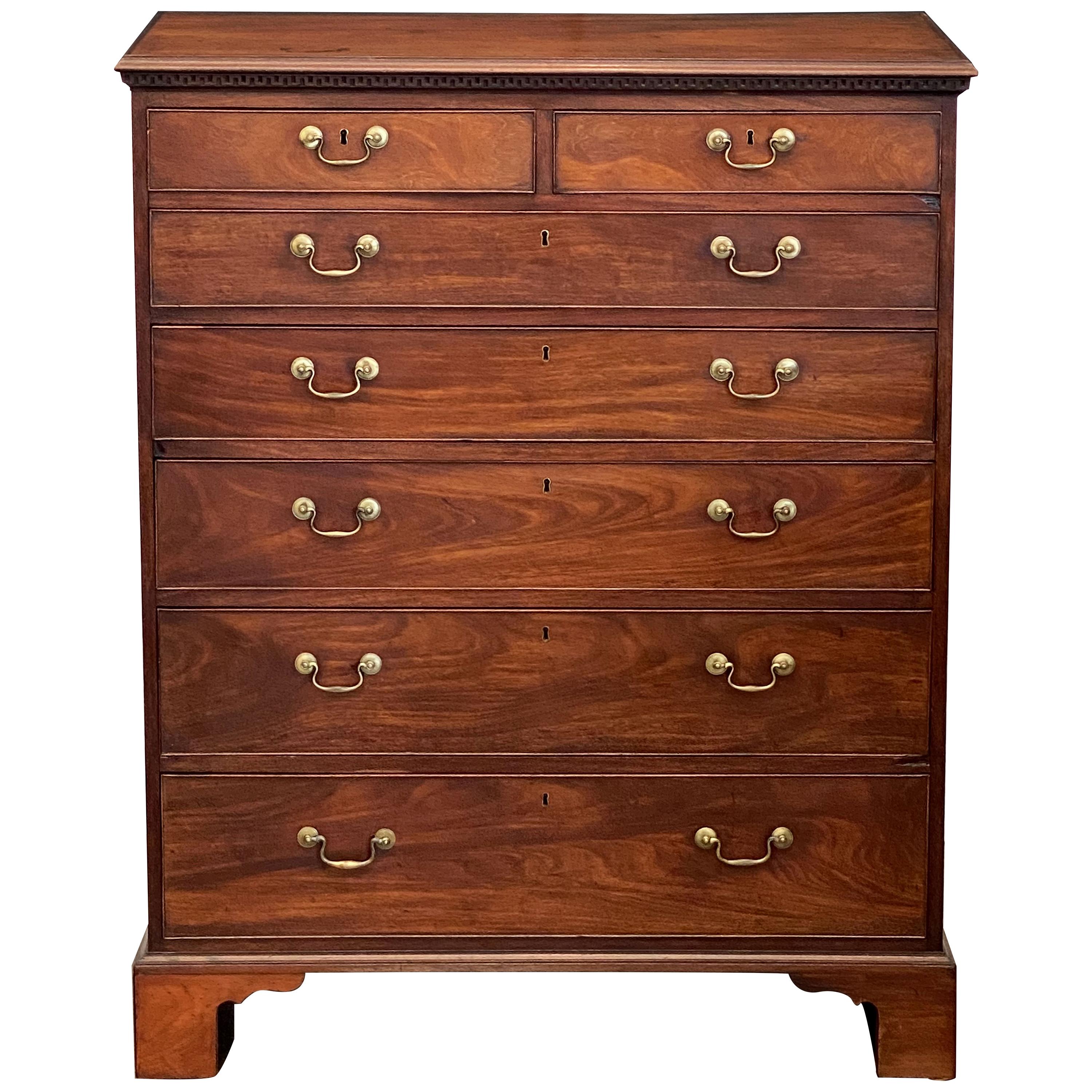 A fine English tall chest or high chest of mahogany from the Georgian period, featuring a rectangular top with Greek Key dentile moulding, over a frieze of two beaded short drawers over five beaded long drawers of ascending size, each drawer with