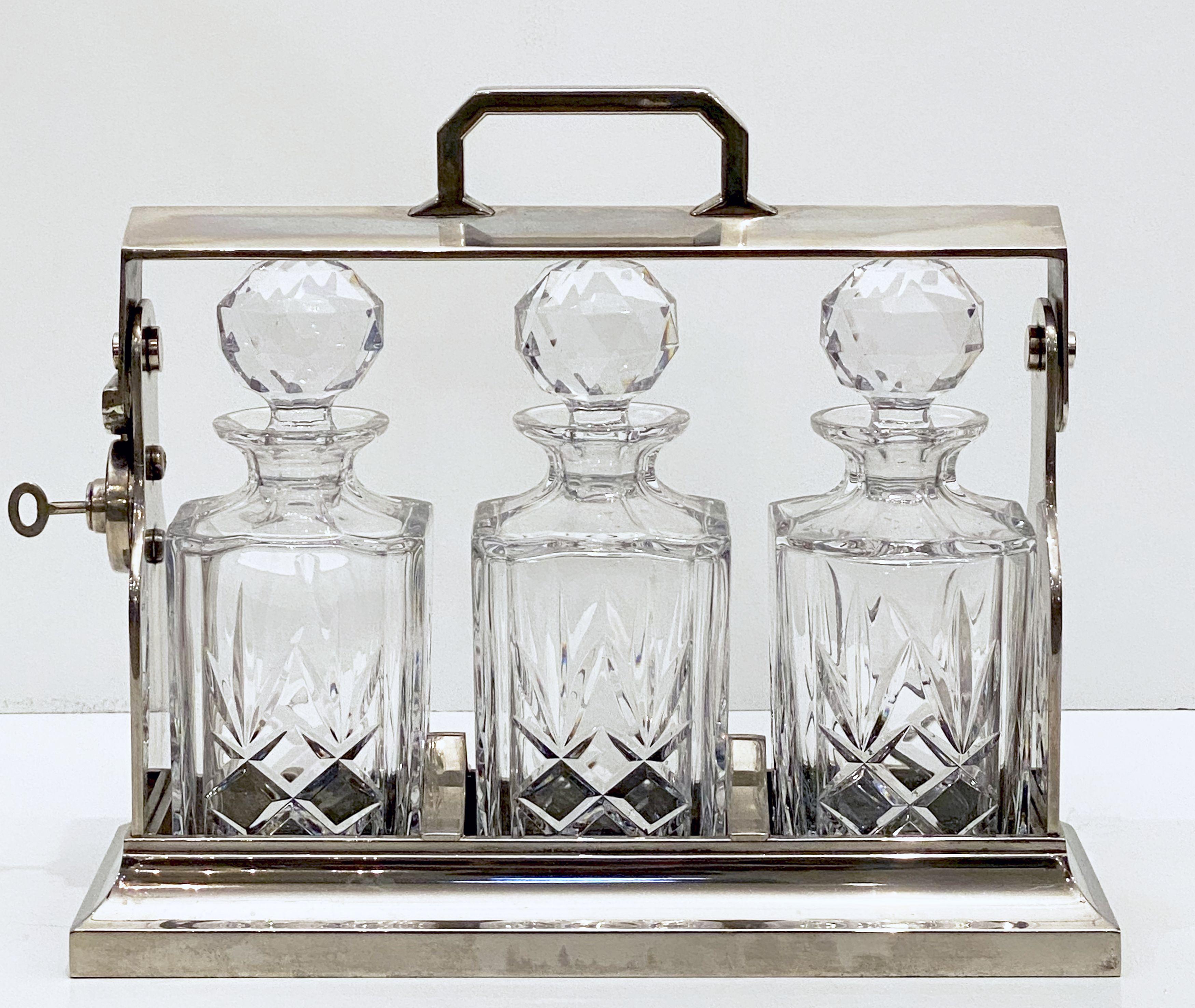 A handsome large Tantalus drinks or spirits decanter set of plate silver from the Edwardian era, c.1900, made by the celebrated English silversmiths, Mappin and Webb.

The case comes with a working key that requires a slight turn left. The lock